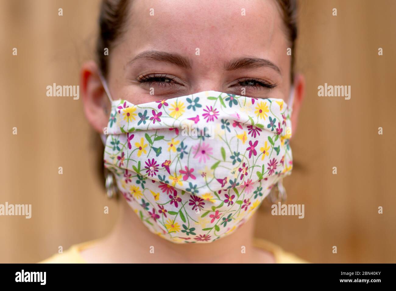 Giovane donna che indossa una maschera faccia in tessuto fatta in casa, Regno Unito Foto Stock