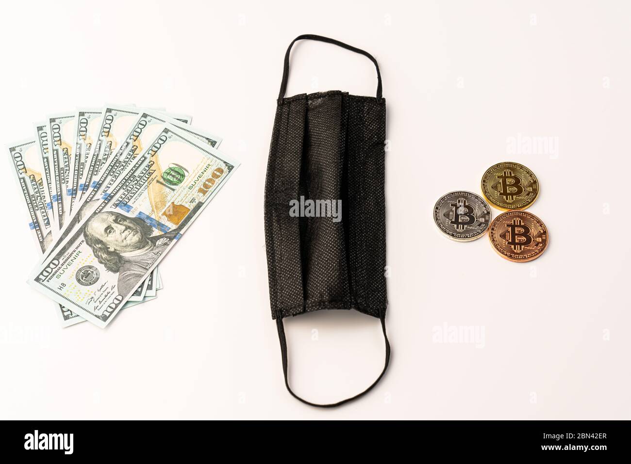 Maschera medica nera su sfondo bianco monete di bitcoin d'oro e dollari USA primo piano Foto Stock