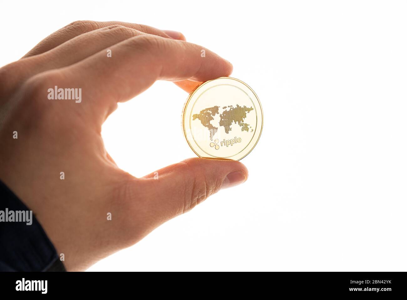 La mano maschio tiene la moneta ondulata dorata isolata su sfondo bianco Foto Stock