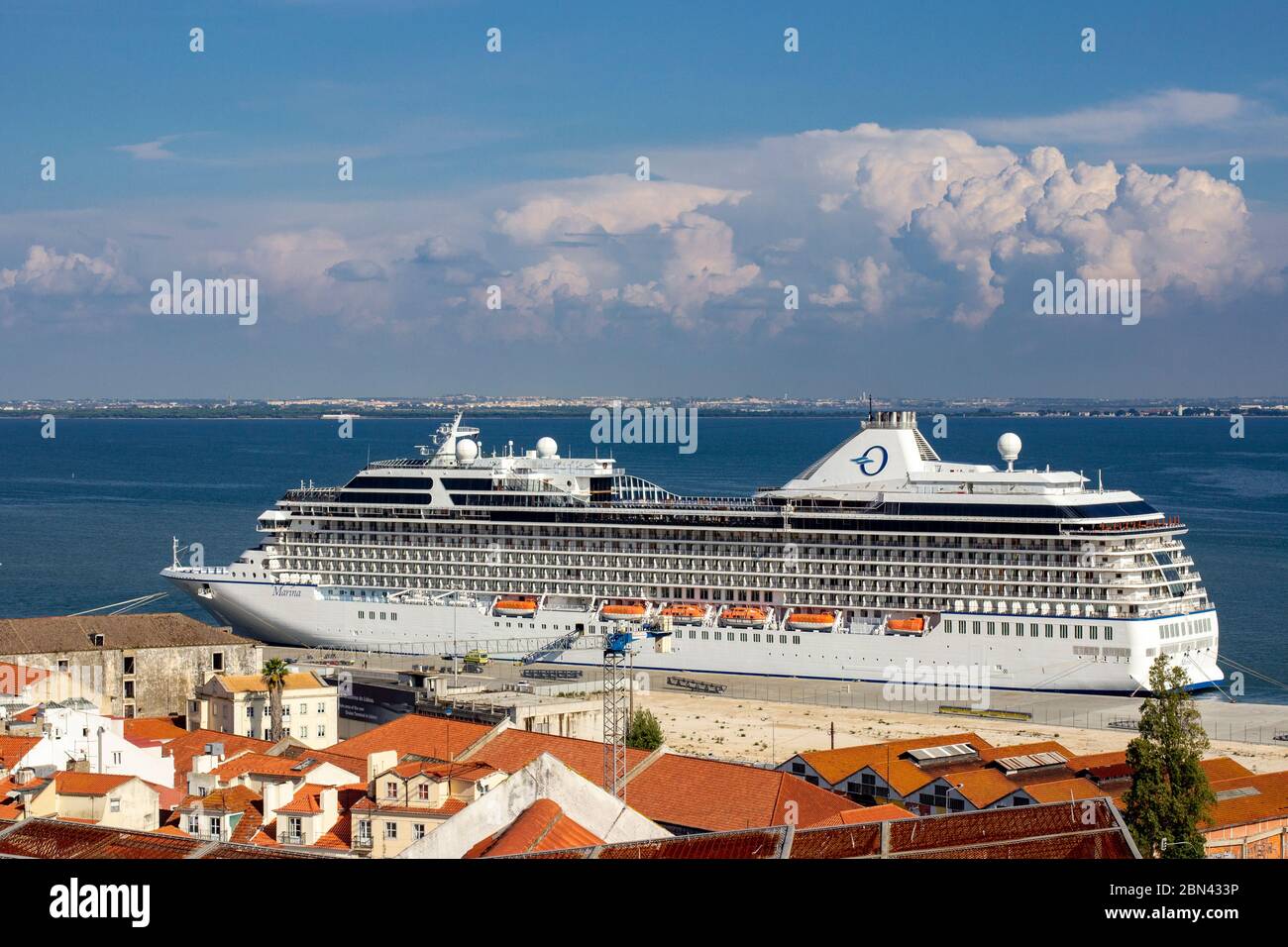 La nave da crociera dell'Oceania Marina è ormeggiata al porto di Lisbona, in Portogallo, con l'oceano e le nuvole sullo sfondo e tetti in tegole in primo piano Foto Stock