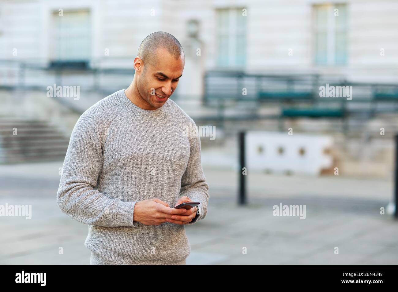 giovane uomo che invia un messaggio di testo sul suo cellulare Foto Stock
