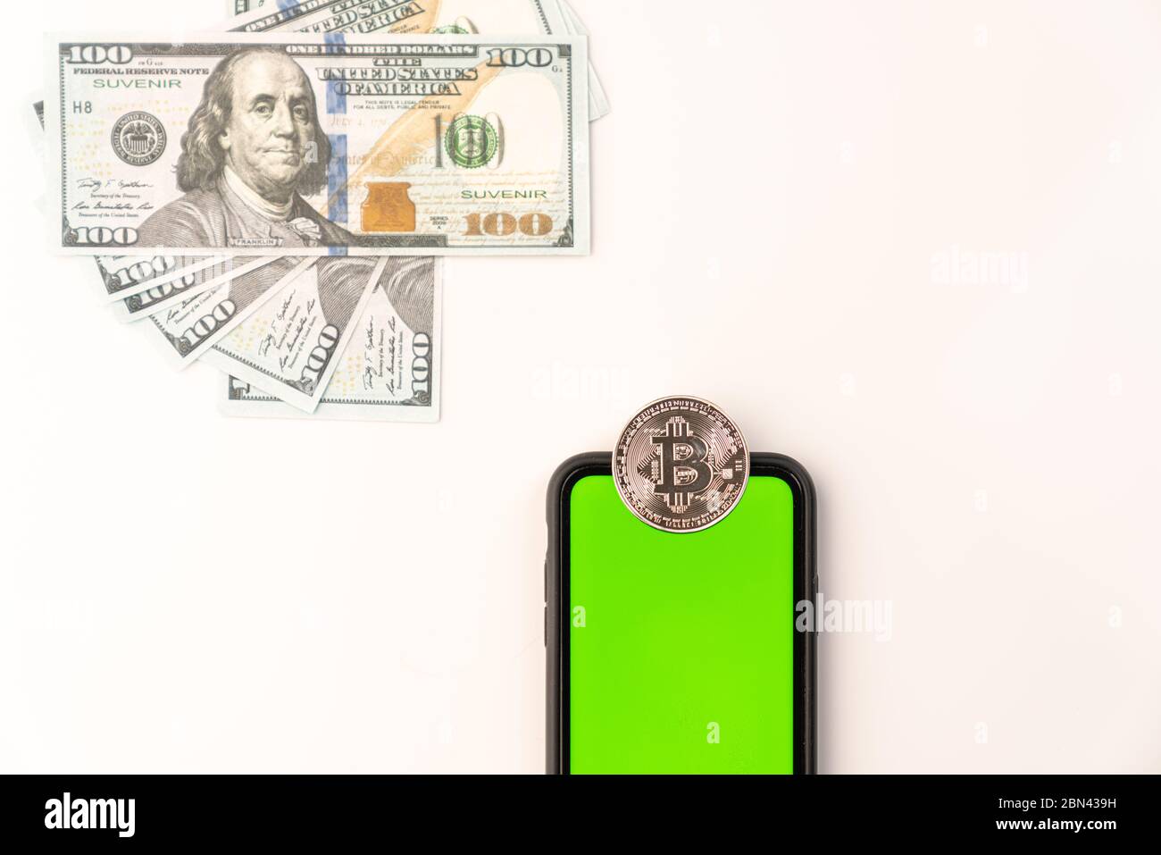 Moneta criptovaluta Bitcoin sul telefono con schermo verde e banconote in dollari isolate su bianco Foto Stock