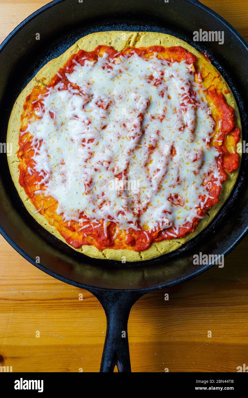 Pizza alla crosta di ceci in una padella di ghisa Foto Stock