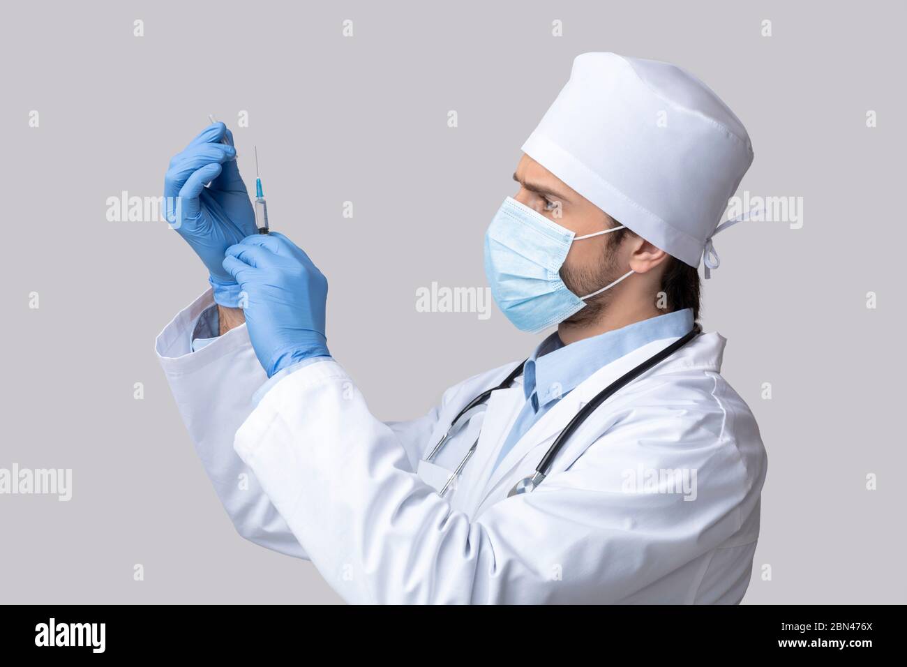 Medico in maschera protettiva che prepara il vaccino per l'iniezione Foto Stock