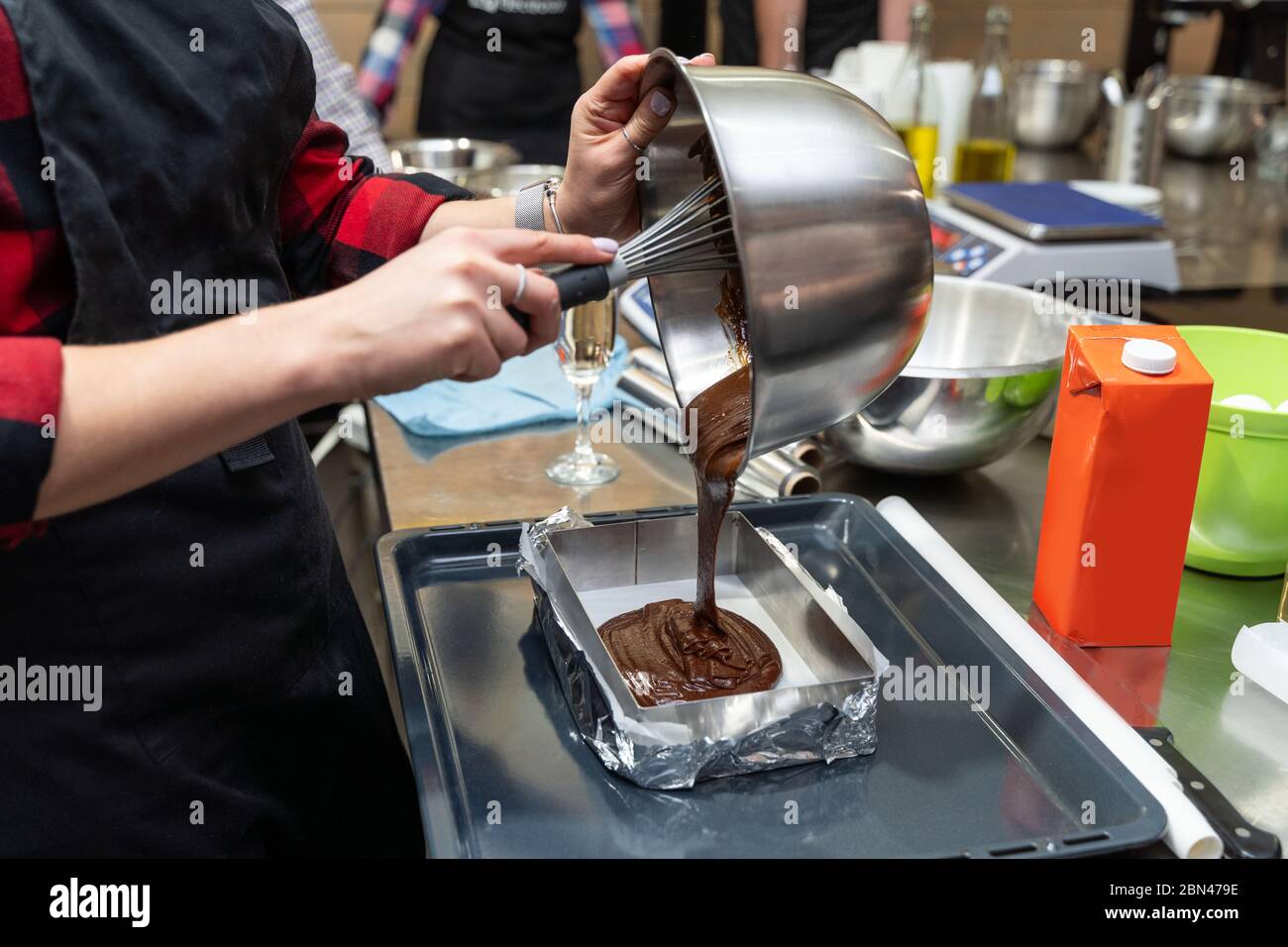 Donna che versa l'impasto di cioccolato in una padella Foto Stock