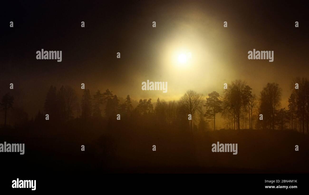 Sole che splende dietro il cielo nebbiato Foto Stock