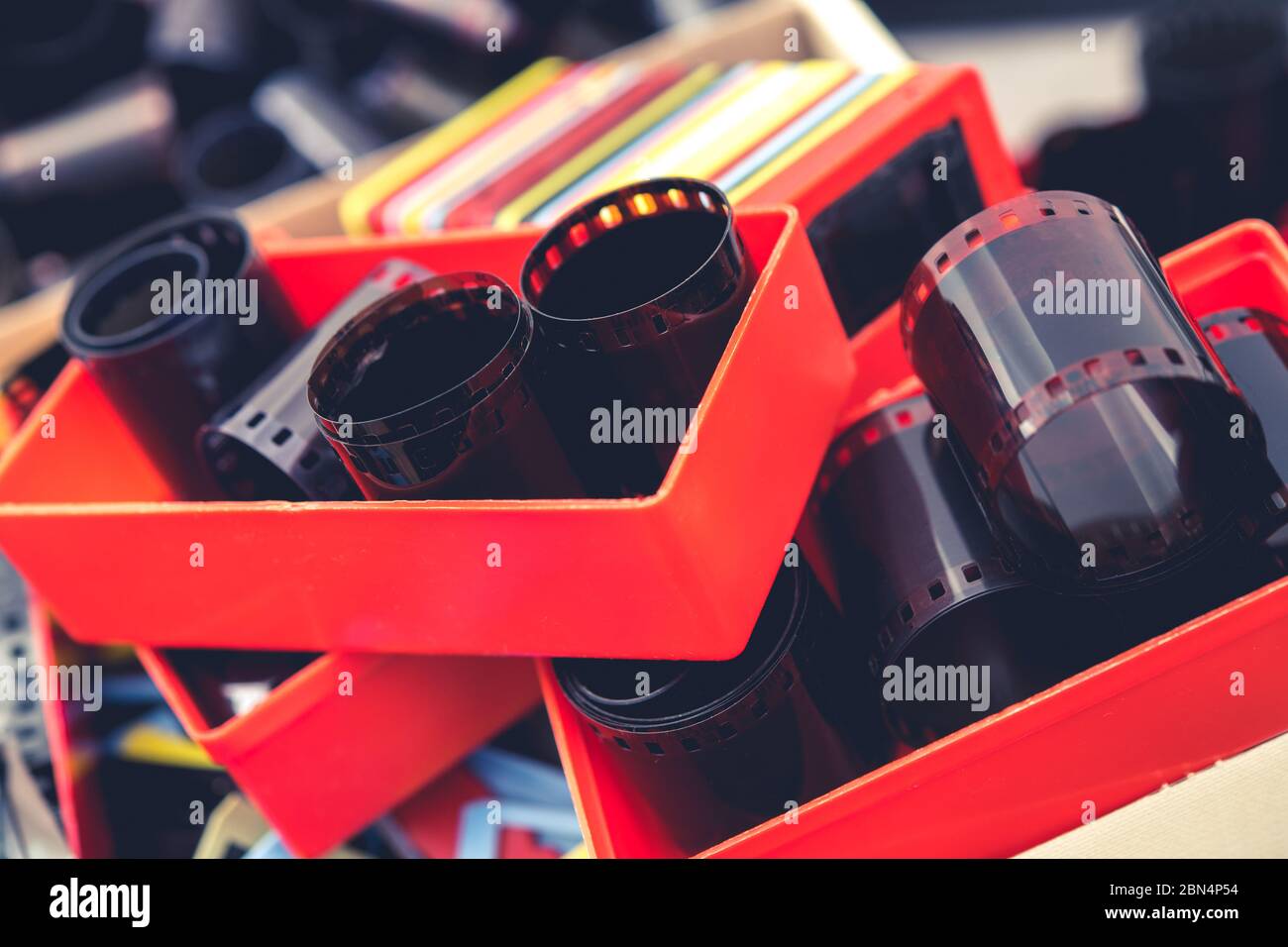 Contenitori riempiti con rotoli di pellicola negativa da 35 mm e supporti per vetrini in plastica con telaio multicolore. Foto Stock