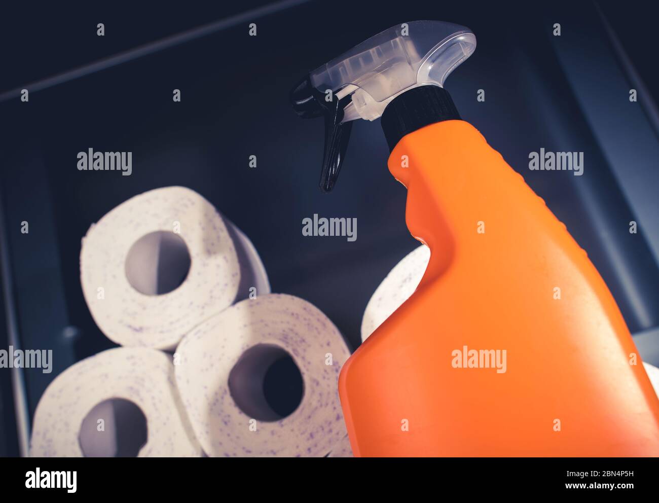 Vista dall'alto del contenitore blu riempito con rotoli di asciugamani di carta e flacone spray arancione con detergente liquido. Foto Stock