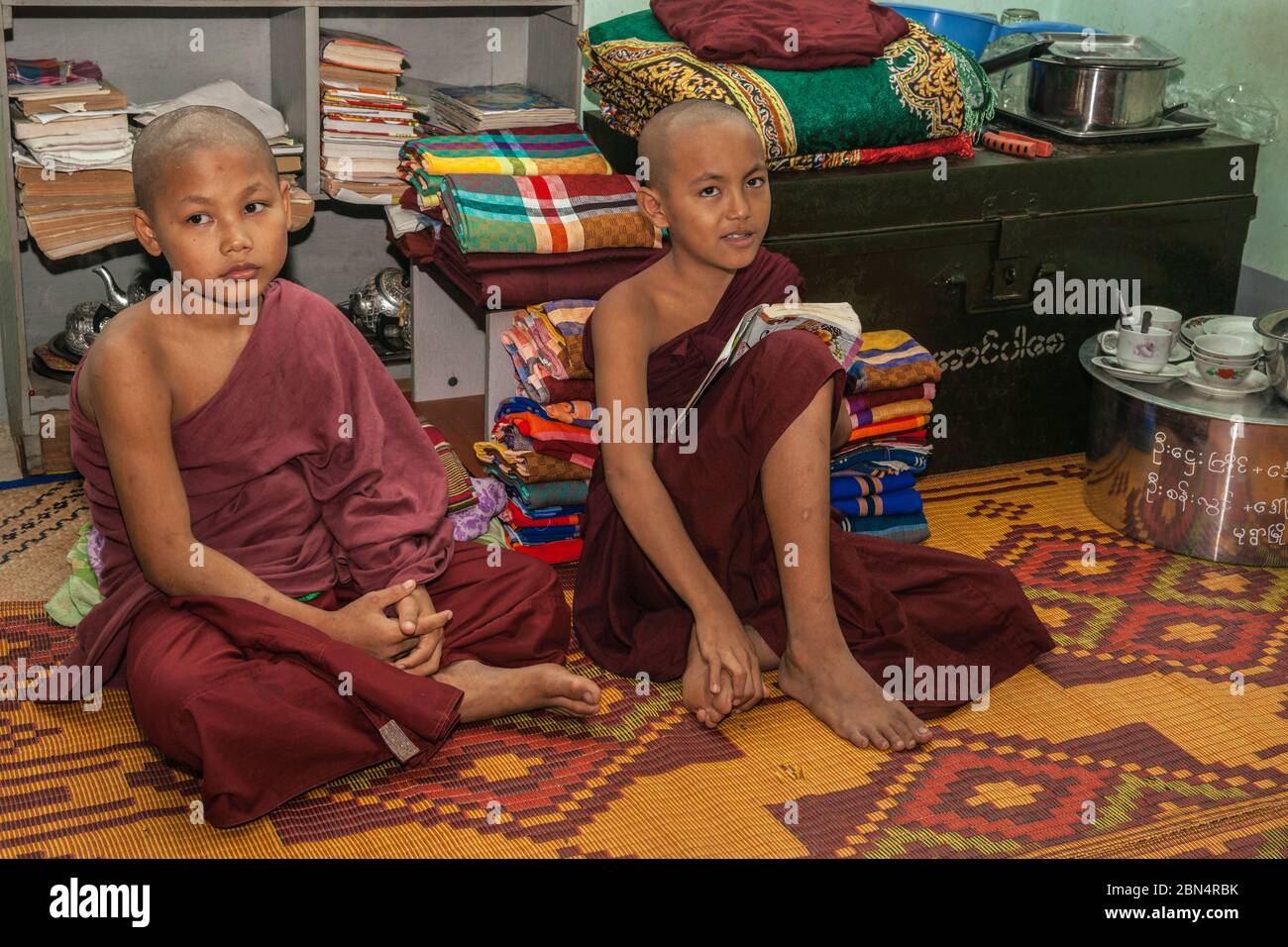 Bagan Myanmar - Ottobre 30 2013; due giovani ragazzi buddisti nella loro stanza circondata da tappeti di formazione come monaci seduti sul piano del monastero.1 Foto Stock