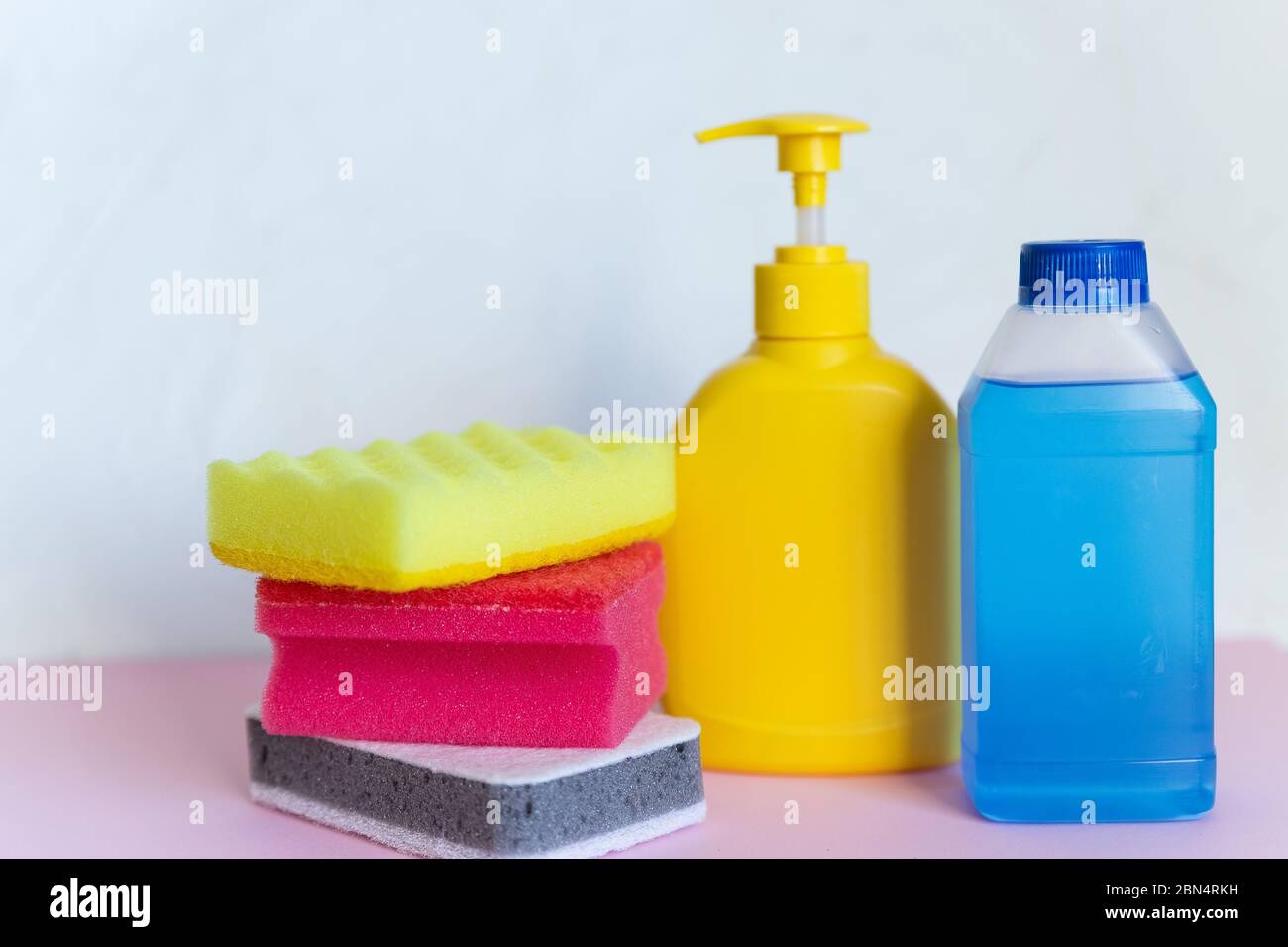 Prodotti chimici per uso domestico su sfondo bianco. Prodotti per la pulizia professionale, pulizia a molla. Contenitori in plastica gialli e blu per detergenti domestici Foto Stock