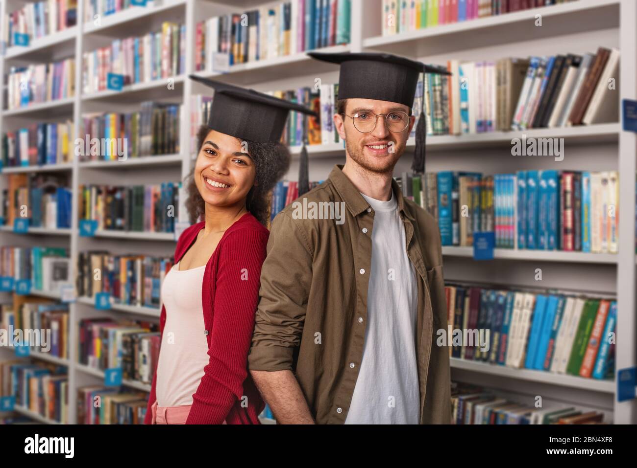 Laureati davanti a una biblioteca. Concetto di preparazione e determinazione Foto Stock