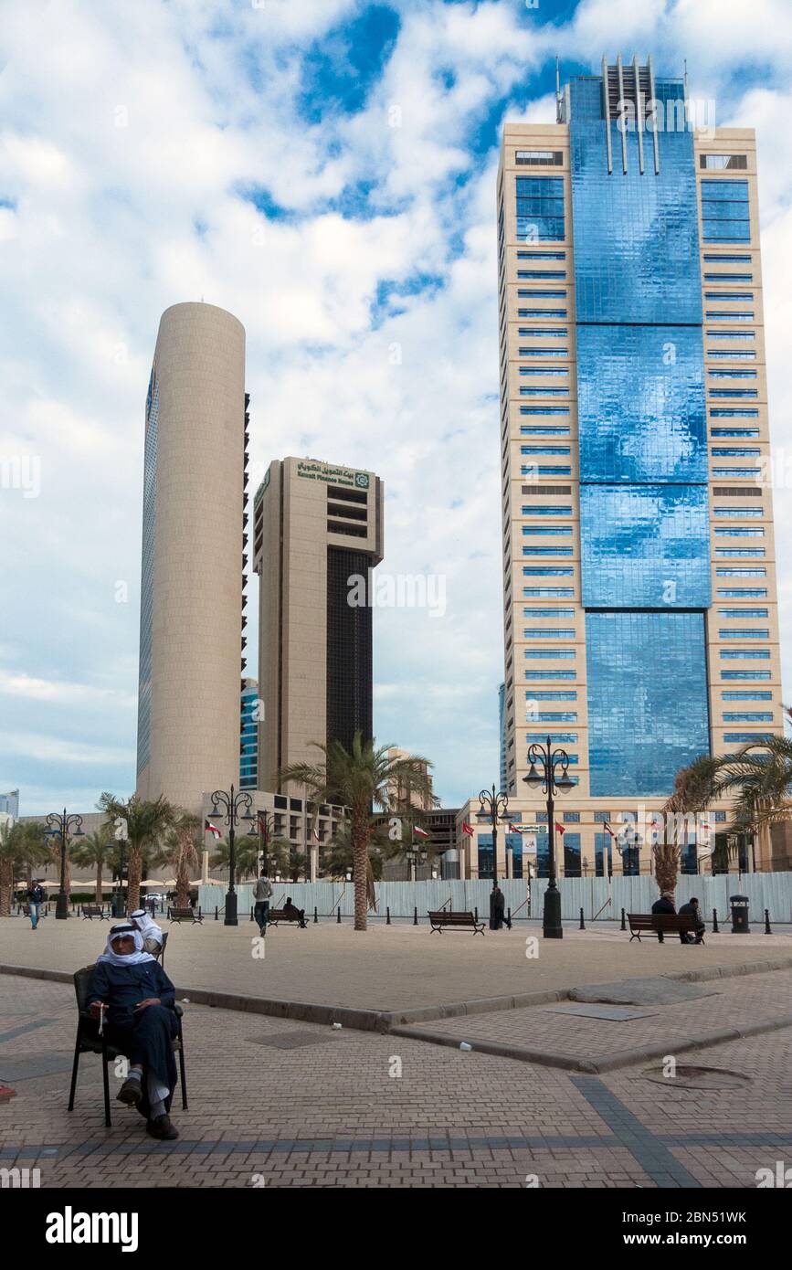 Kuwait città, Kuwait: Un uomo arabo siede da solo di fronte ai grattacieli del centro della città di Kuwait Foto Stock