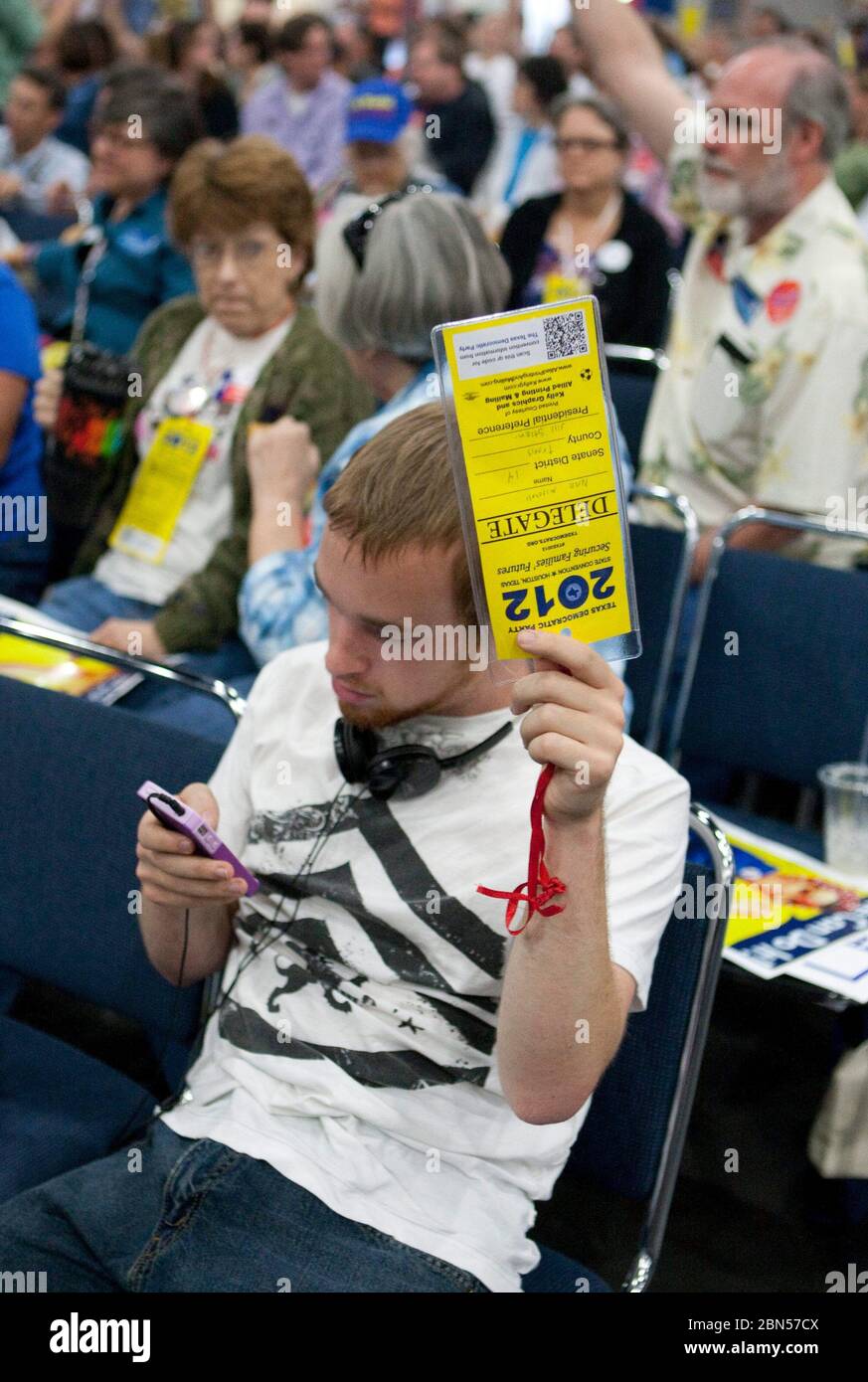 Houston, Texas USA, 9 giugno 2012: Giovane partecipante maschile alla Texas state Democratic Convention guarda il suo telefono cellulare mentre tiene in mano la sua carta delegata ufficiale durante una riunione d'affari. © Marjorie Kamys Cotera/Daemmrich Photography Foto Stock