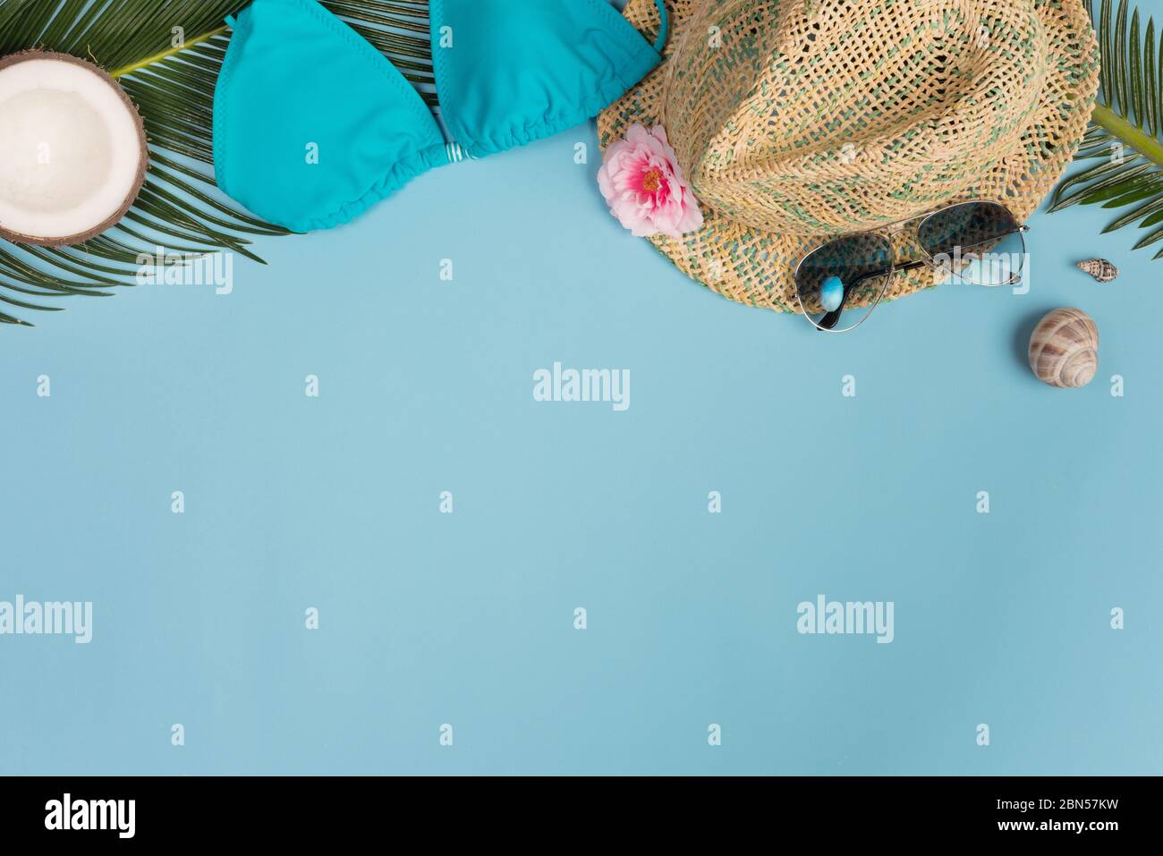 Composizione estiva. Foglie tropicali, abito, cappello, cocco su sfondo blu. Concetto estivo. Disposizione piatta, vista dall'alto, spazio per la copia Foto Stock