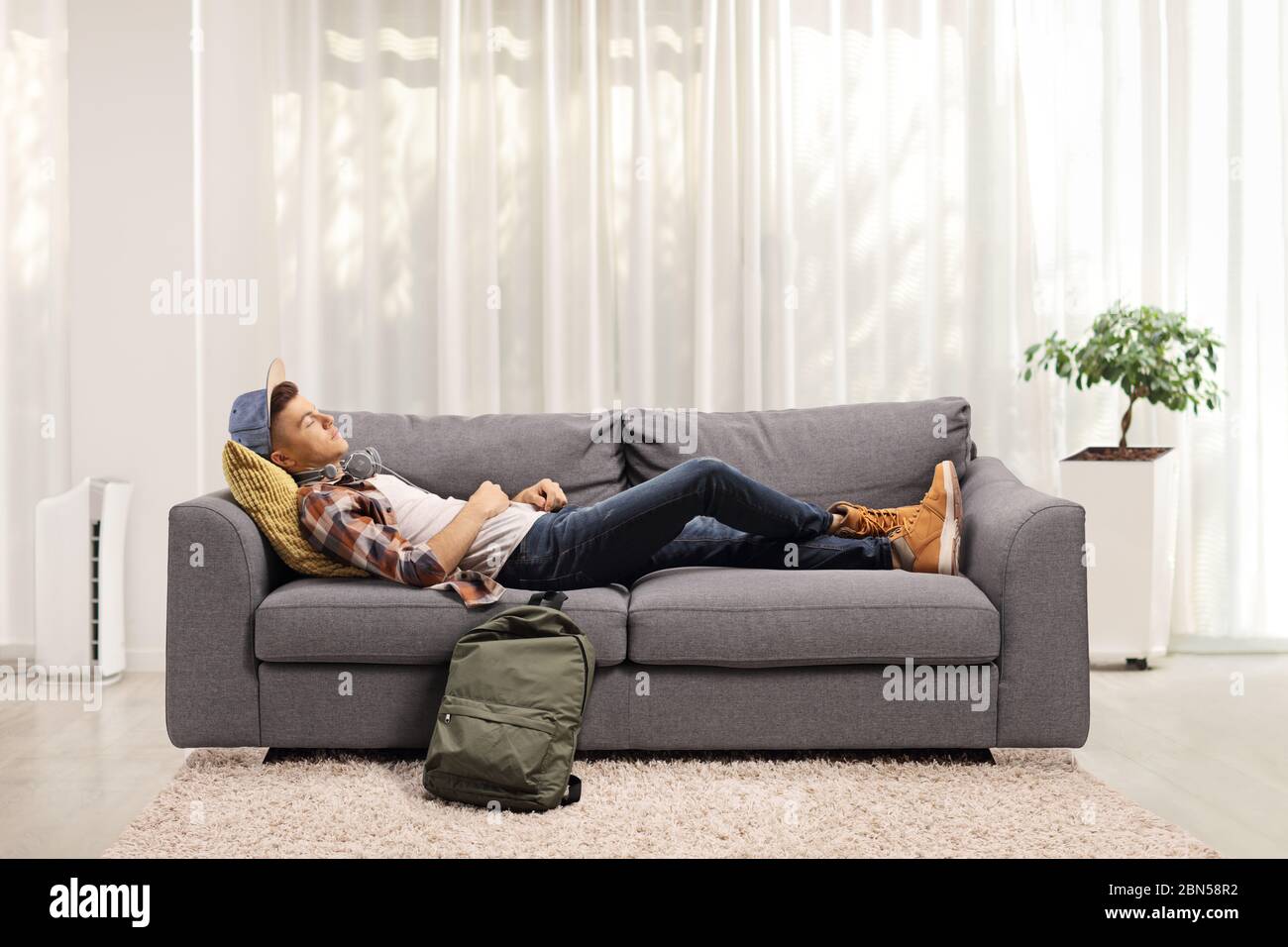 Studente maschile che dorme su un divano a casa Foto Stock