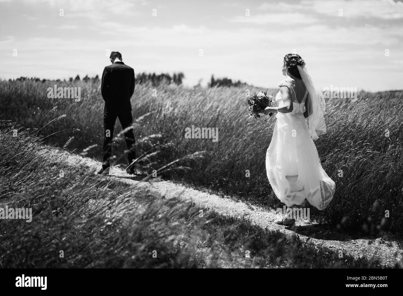foto di uno sposo e di una sposa che cammina in un campo Foto Stock