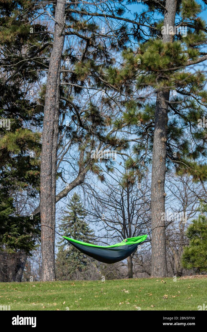 St. Paul, Minnesota. Parco di Como. Un uomo che pratica il sociale di distanziare isolandosi in un'amaca in una bella giornata nel parco. Foto Stock