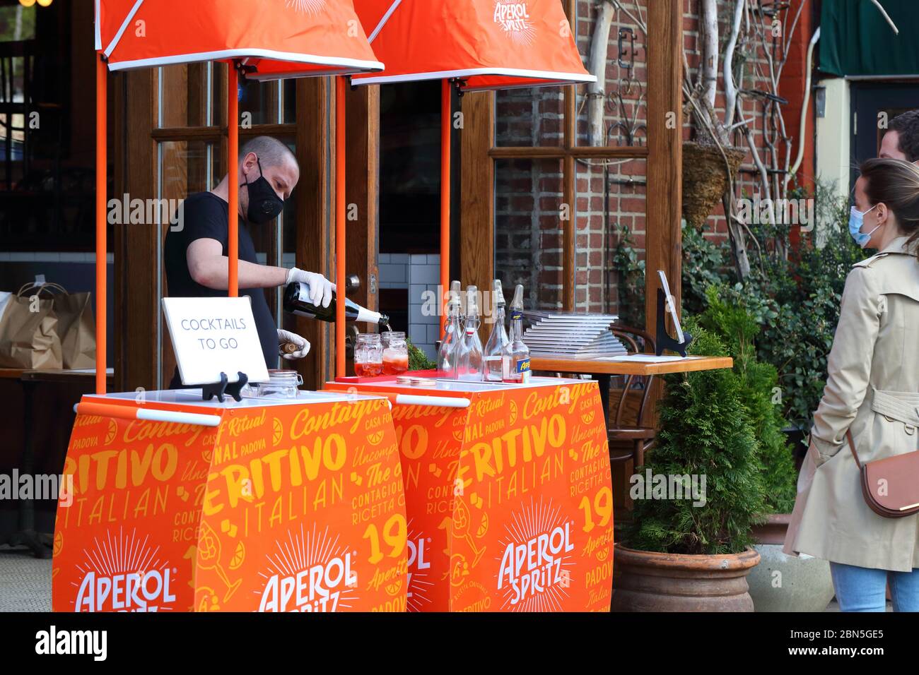 Un barista versa un Aperol Spritz in una stazione cocktail da asporto fuori dal ristorante Boucherie a New York durante la crisi del Coronavirus COVID-19. Foto Stock