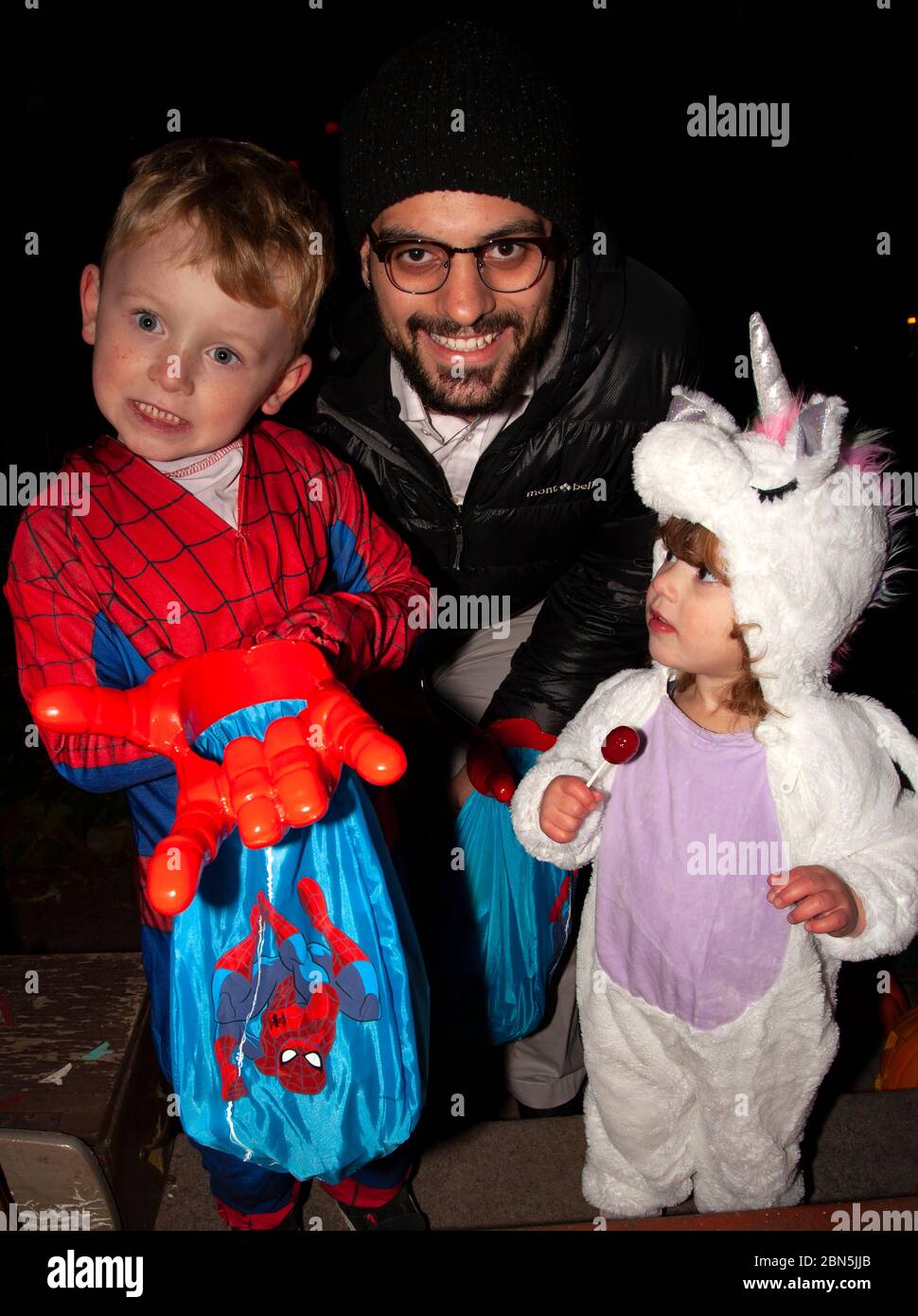 Spiderman e Baby Unicorn con il padre per una notte Halloween trucchi o tratta. St Paul Minnesota, Minnesota, USA Foto Stock