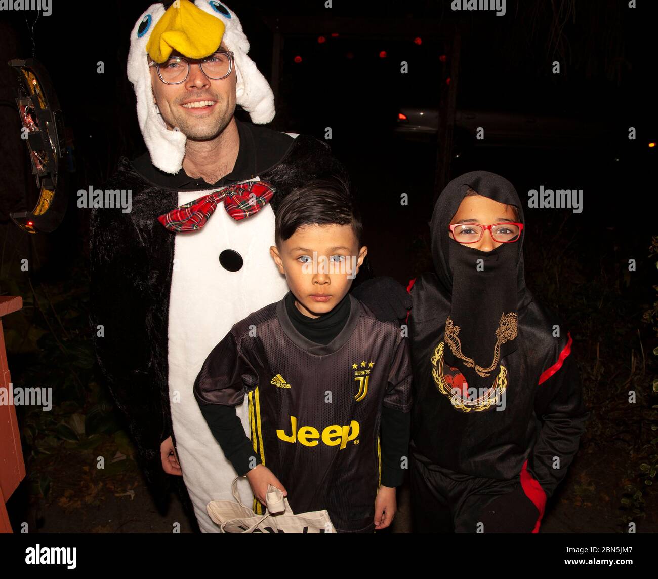 Bambini in costume con il loro pinguino padre fuori per Halloween e trucchi e delizie. St Paul Minnesota, Minnesota, USA Foto Stock