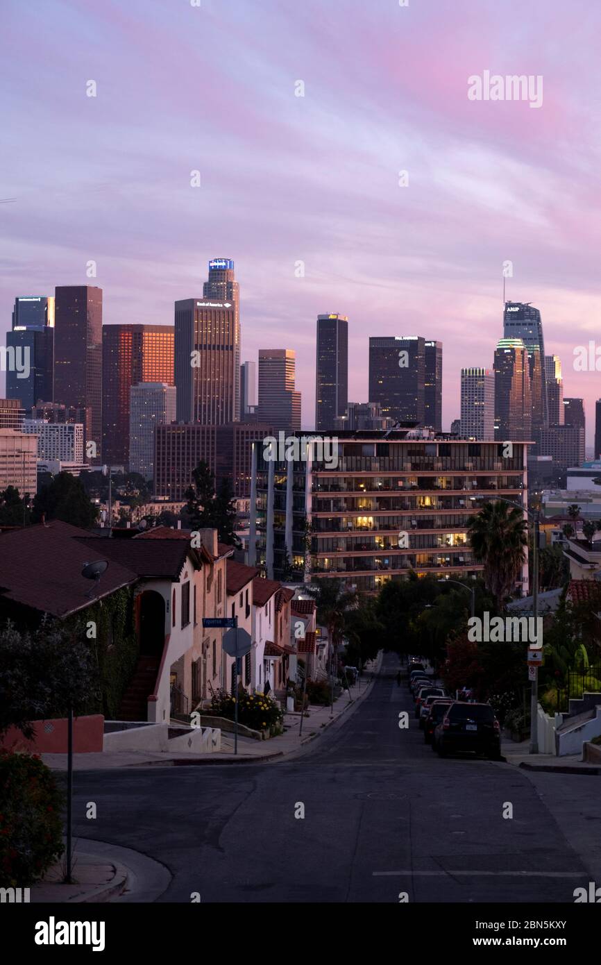 Guardando una strada verso lo skyline del centro di Los Angeles sotto un cielo rosa al tramonto Foto Stock