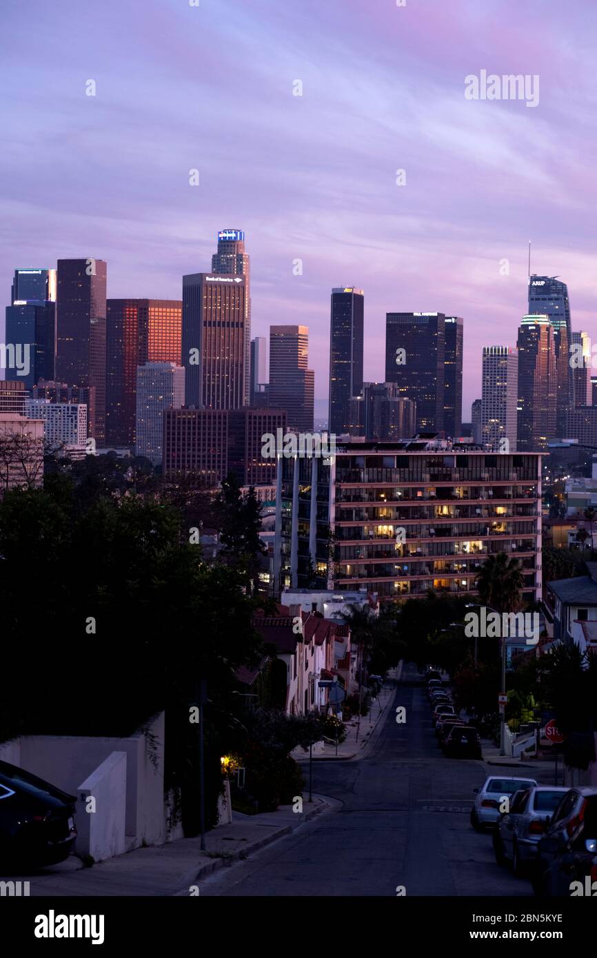 Guardando una strada verso lo skyline del centro di Los Angeles sotto un cielo rosa al tramonto Foto Stock
