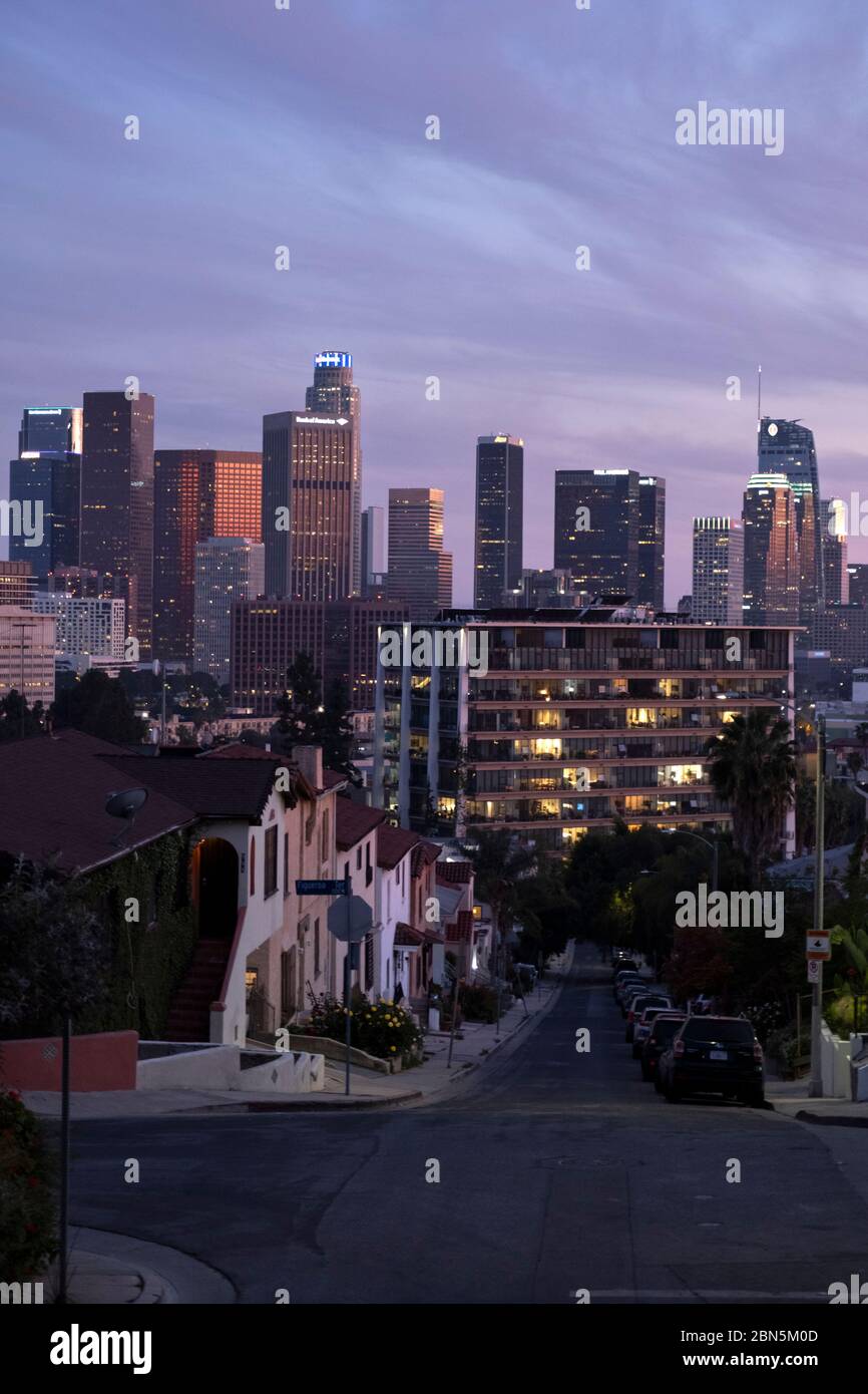 Guardando una strada verso lo skyline del centro di Los Angeles sotto un cielo rosa al tramonto Foto Stock