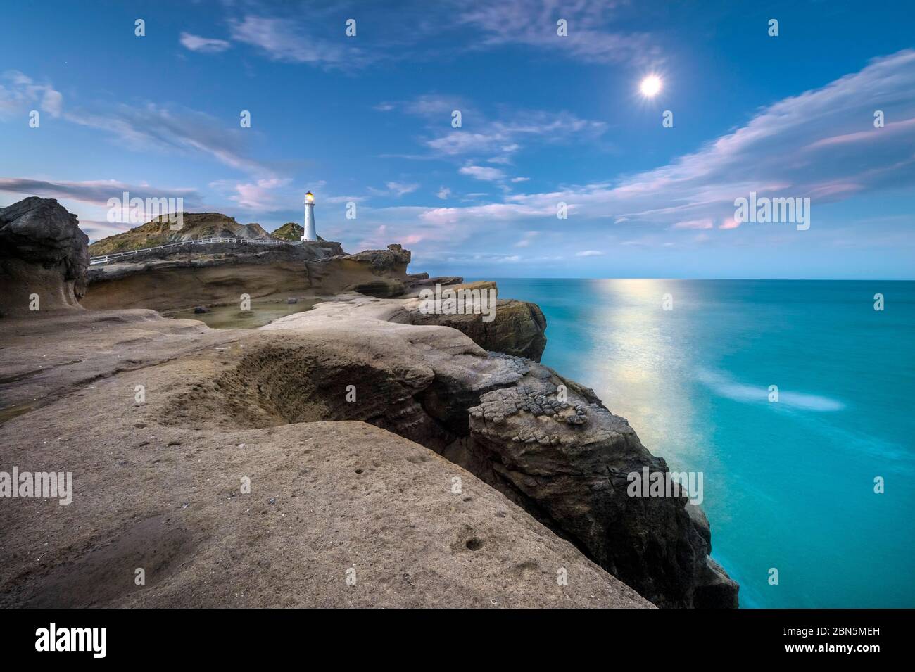 Faro a luna piena sulle scogliere di roccia lavica a Castlepoint, Masterton, Wellington, Nuova Zelanda Foto Stock