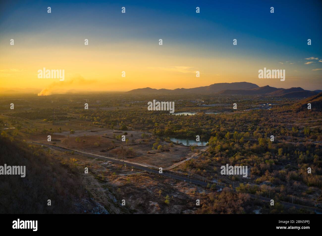 Questa foto unica mostra il paesaggio di Hua Hin! In primo piano una strada di campagna e lago. Sullo sfondo si possono vedere le colline e il tramonto Foto Stock