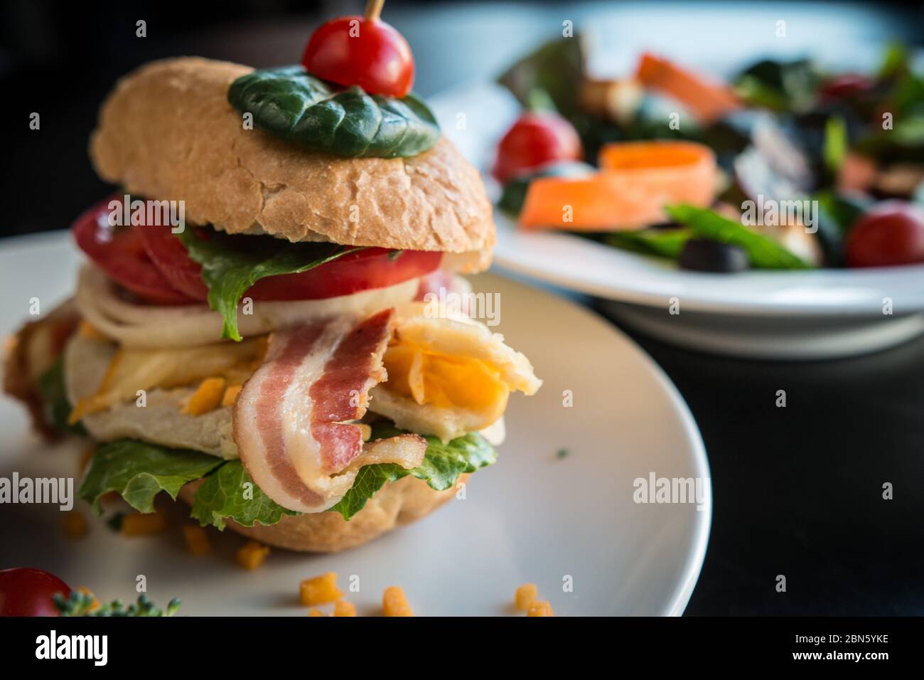 Primo piano immagine di hamburger caricato con patina baguette e un piatto di insalata. Foto Stock