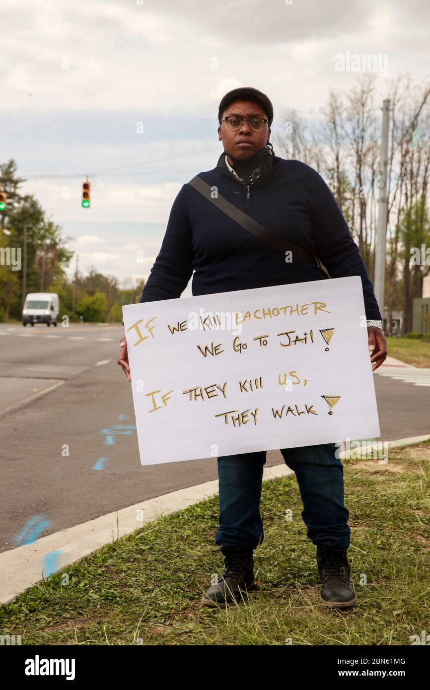 Indianapolis, Stati Uniti. 12 maggio 2020. Un protesta detiene un cartello che dice che se ci uccideremo a vicenda andiamo in prigione! Se ci uccidono camminano! All'angolo di 62nd Street e Michigan Road vicino a dove un ufficiale del Dipartimento di polizia Metropolitano di Indianapolis ha sparato fatalmente a Dreasjon Reed, 21, dalla settimana scorsa a Indianapolis Credit: SOPA Images Limited/Alamy Live News Foto Stock