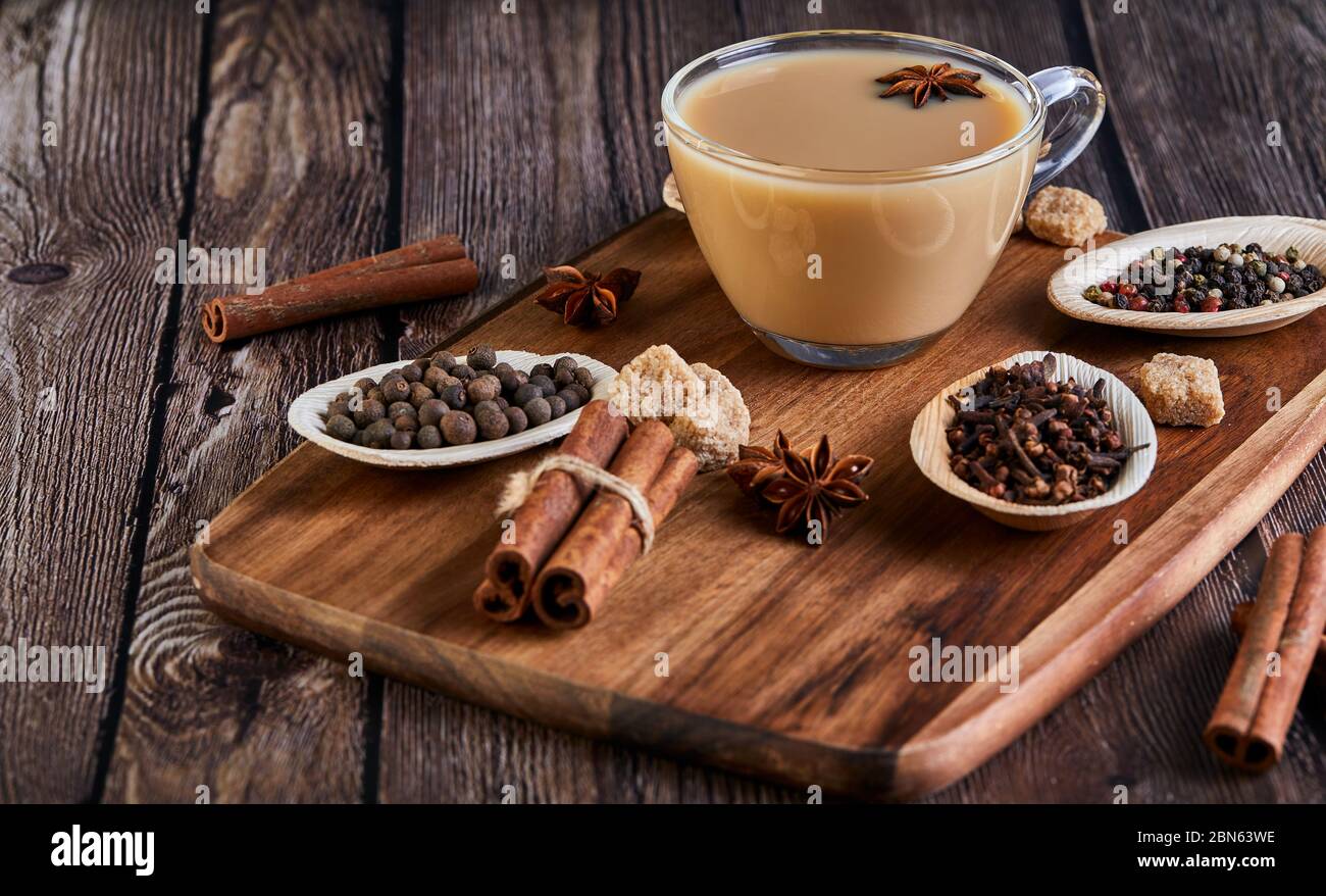 Bevanda indiana tradizionale - tè masala con spezie. Cannella, cardamomo, anice, zucchero, chiodi di garofano, pepe su sfondo di legno scuro. Spazio di copia. Vista laterale Foto Stock