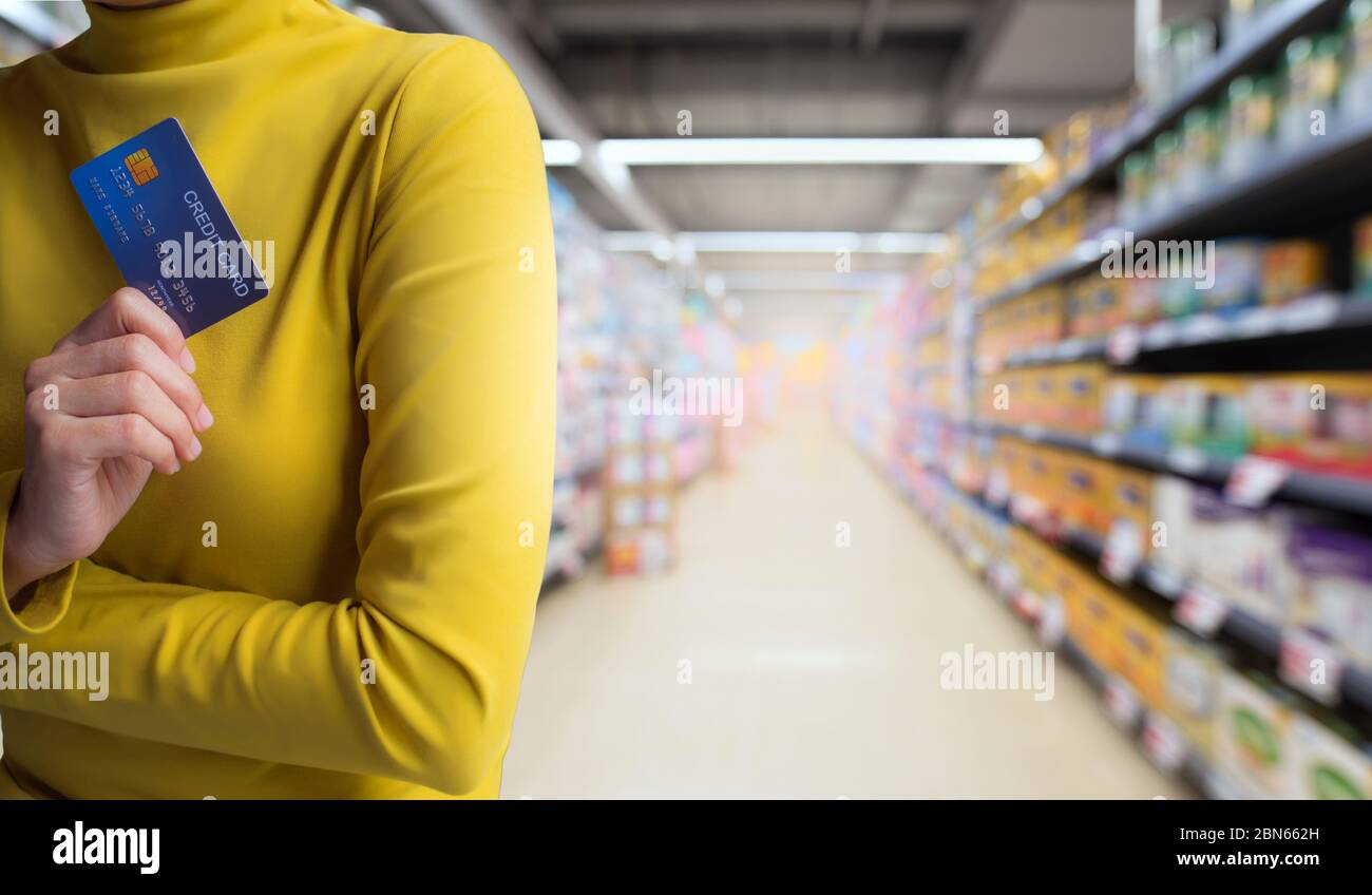 Le mani della donna tengono la carta di credito isolato sullo sfondo del negozio. Foto Stock