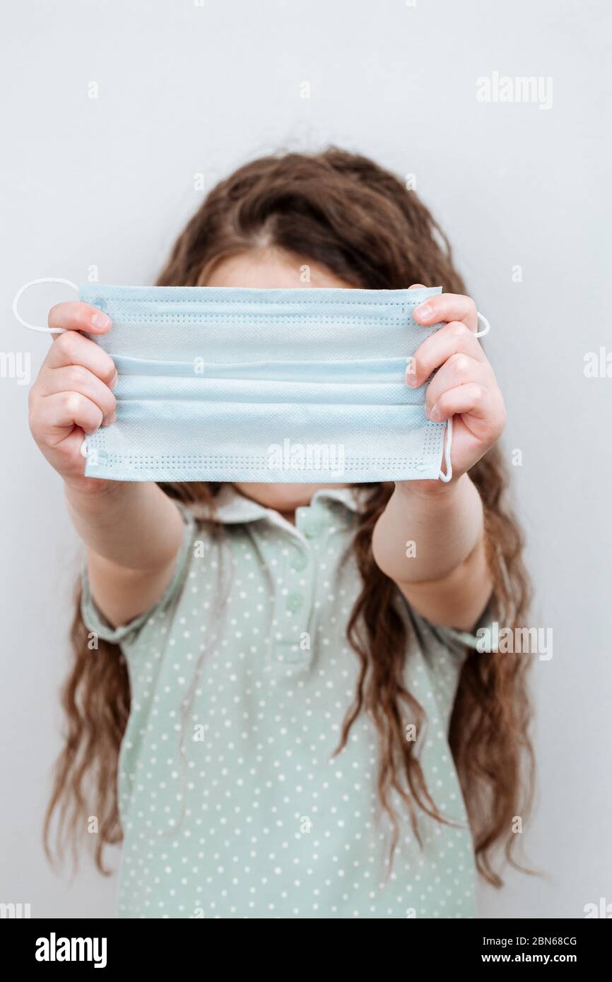 Una ragazza tiene una maschera medica nelle sue mani. Maschera protettiva per la diffusione del virus. Foto Stock