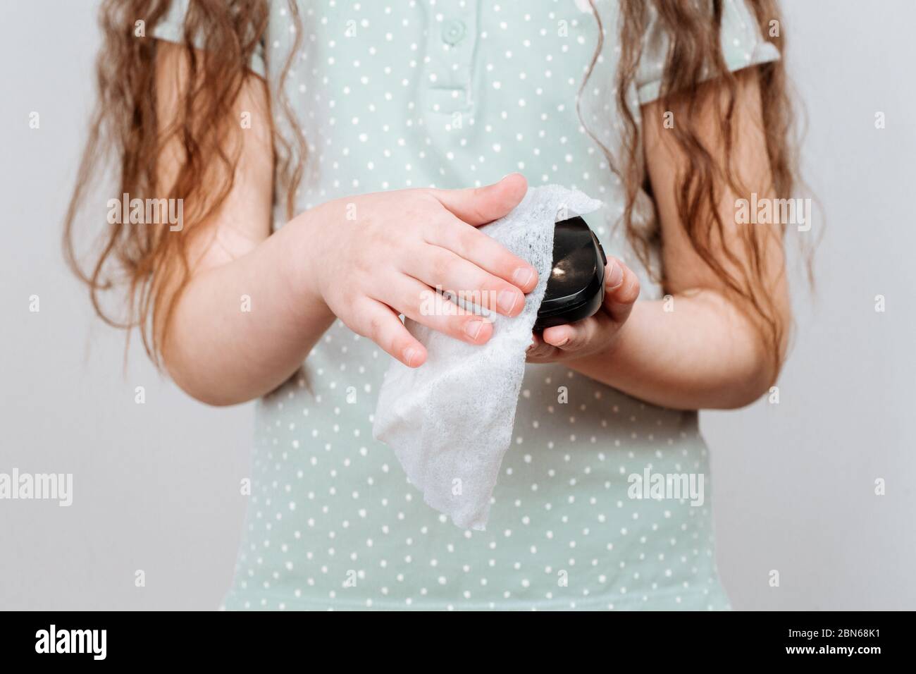 Una ragazza pulisce un mouse per computer con un panno disinfettante. Pulizia e disinfezione del virus corona Foto Stock