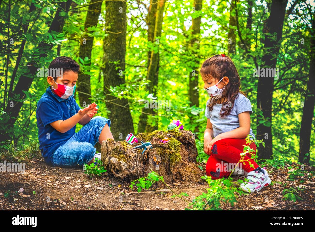 nuovo sfondo normale coronavirus - bambino giocare maschera facciale e sociale di distanza nella foresta per evitare incontri Foto Stock