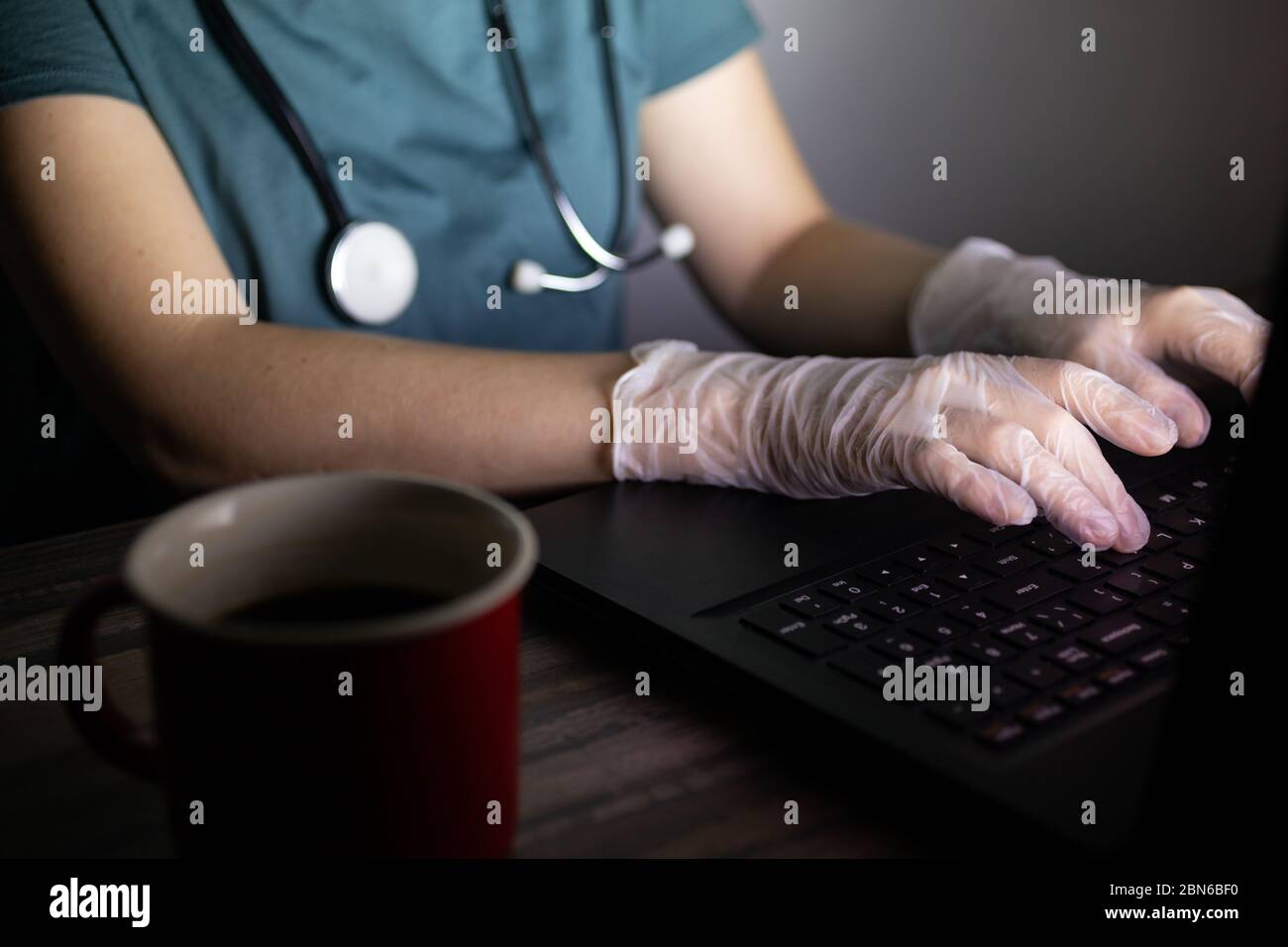 Le mani del medico o dell'infermiere sulla tastiera al buio. Ore lunghe o lavoro straordinario del concetto di lavoratore medico. Foto Stock