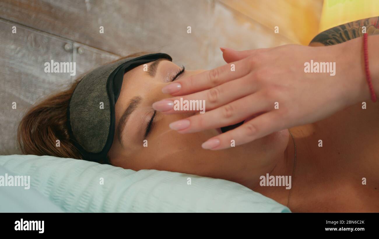 Closeup bella donna in pigiama che brulica mentre coprendo gli occhi con maschera di sonno. Foto Stock