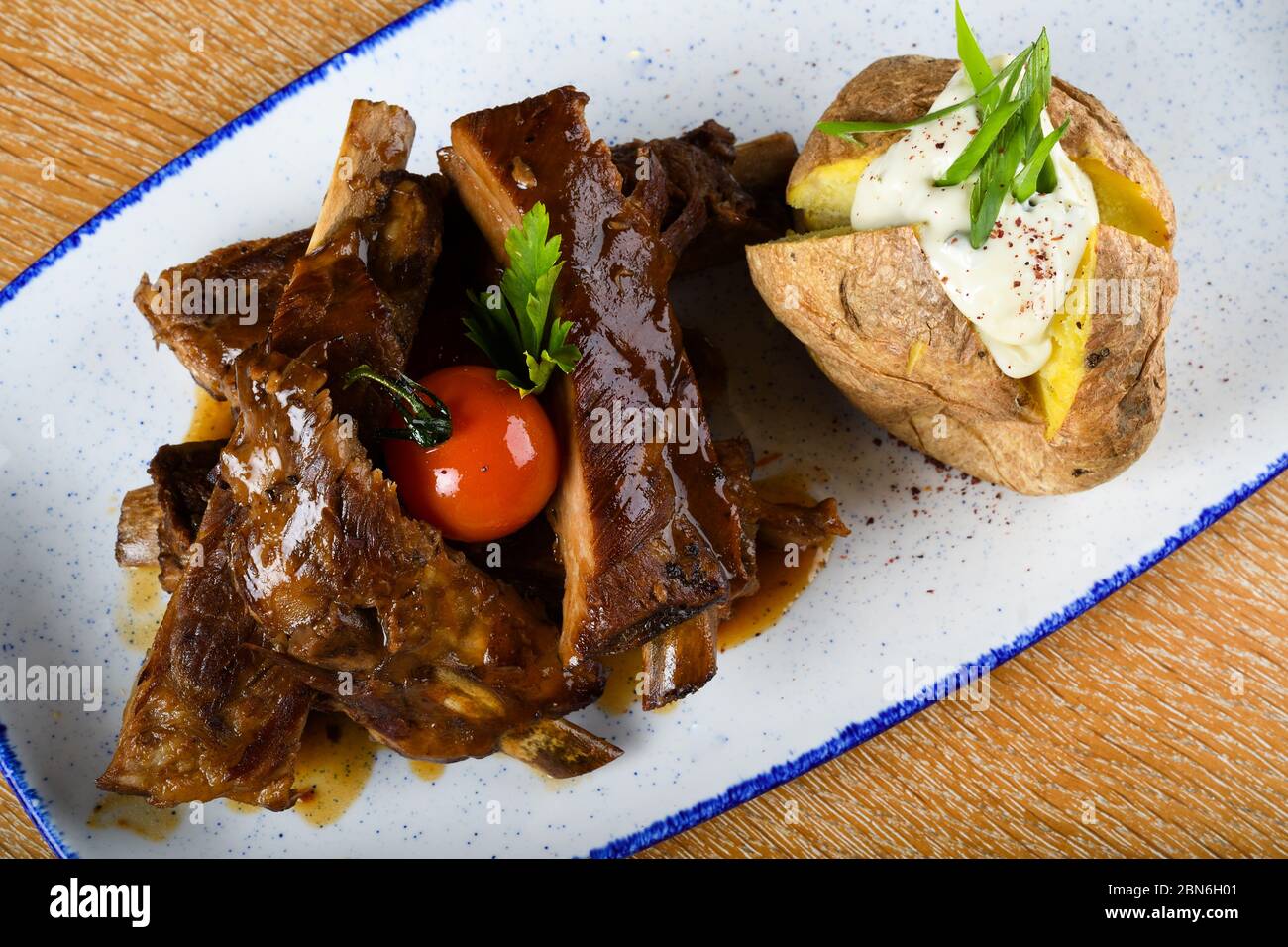 Costolette di ricambio calde e speziate di un barbecue estivo servite con peperoncino caldo e pomodori freschi su un vecchio tagliere di legno d'epoca. Cibo fresco Bu Foto Stock