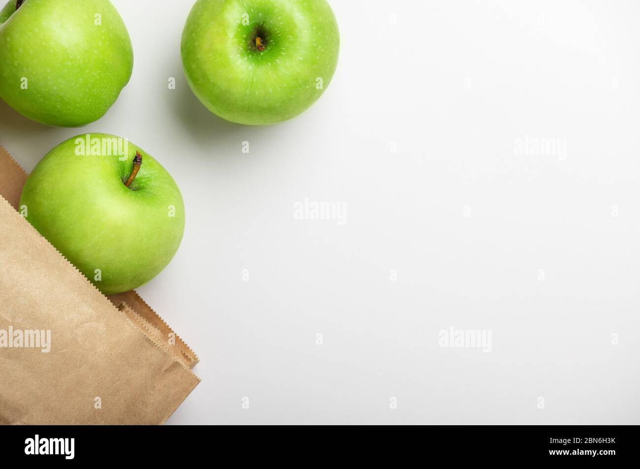Vista dall'alto delle mele in sacchetto di carta su sfondo bianco con ombra. Prodotti ecocompatibili. Alimenti naturali. Frutta succosa. Vitamine per la gente. Verde maturo a. Foto Stock