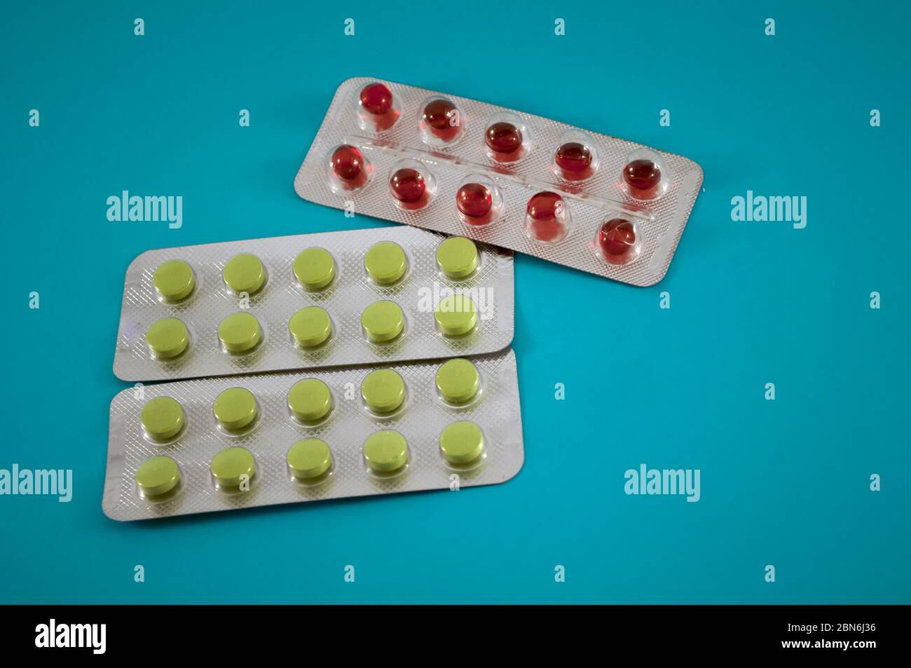 Blister di pillole rosse e verdi, vitamine, compresse, medicinali su sfondo blu Foto Stock