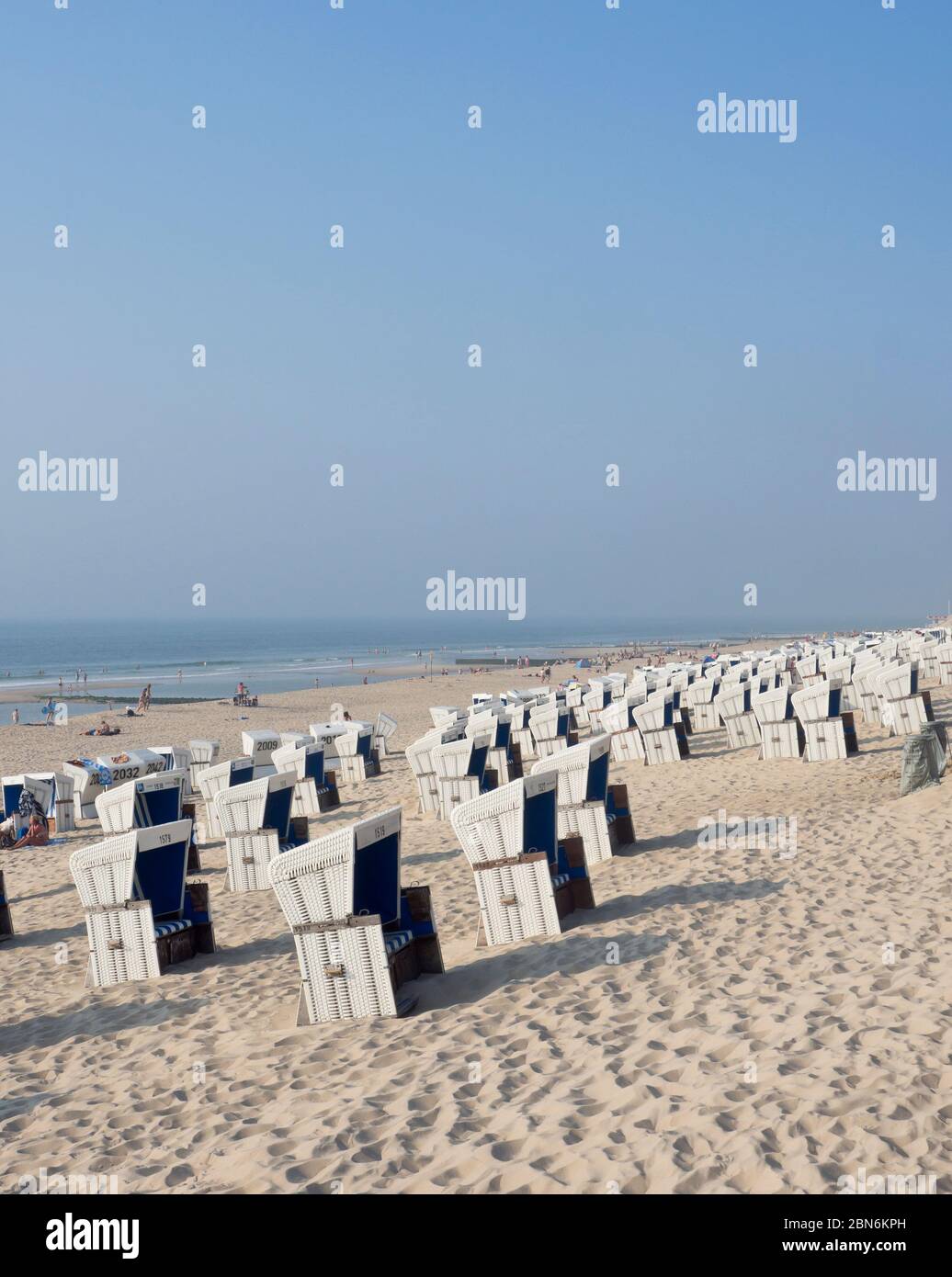 Strandkorb le sedie da spiaggia tedesche, i villeggianti e l'orizzonte lontano lungo i chilometri di spiaggia a Westerland Sylt, in Schleswig-Holstein Germania Foto Stock