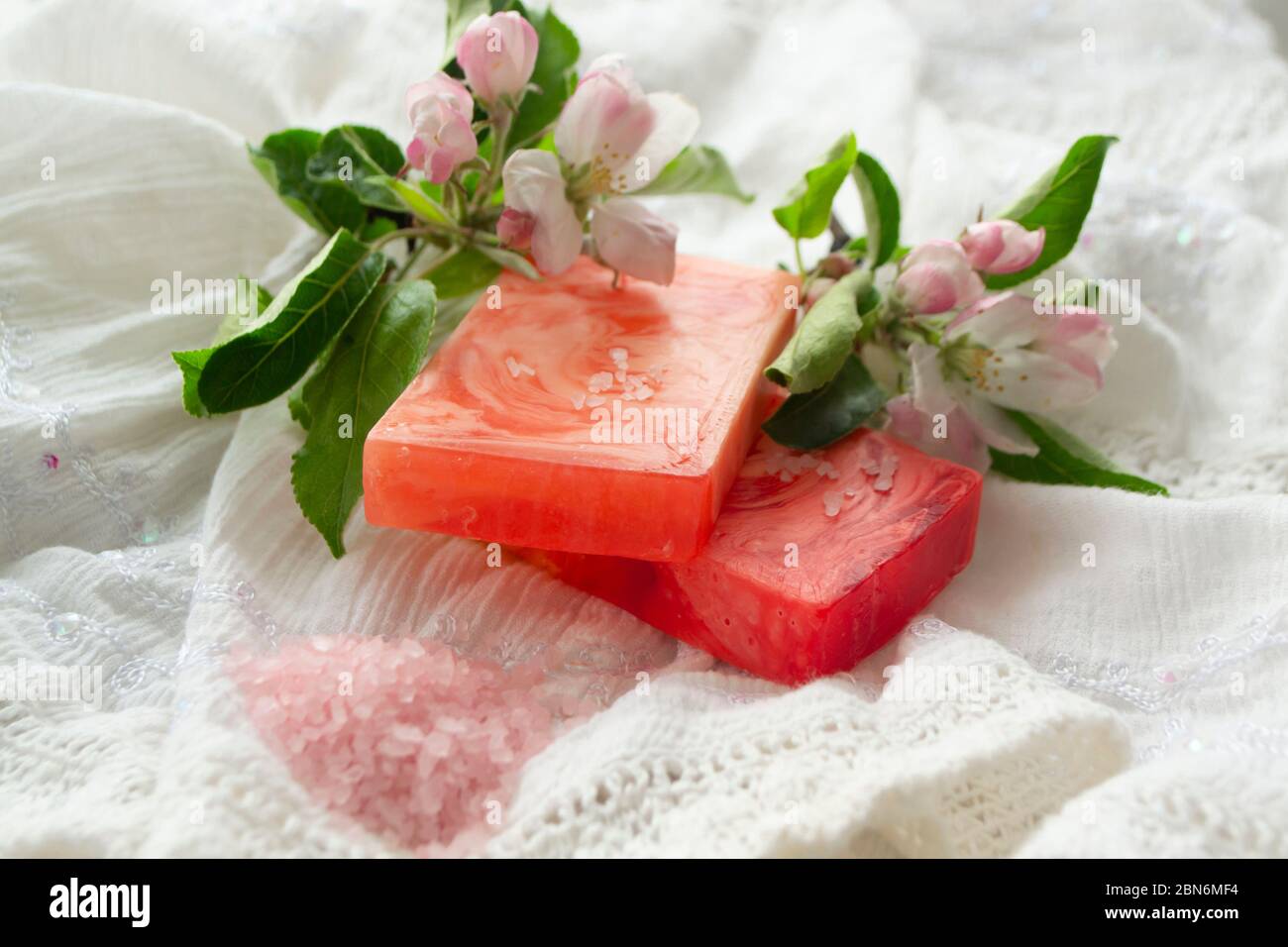 Un bagno con saponi e fiori naturali. Aromaterapia. Fiori di mela Foto Stock