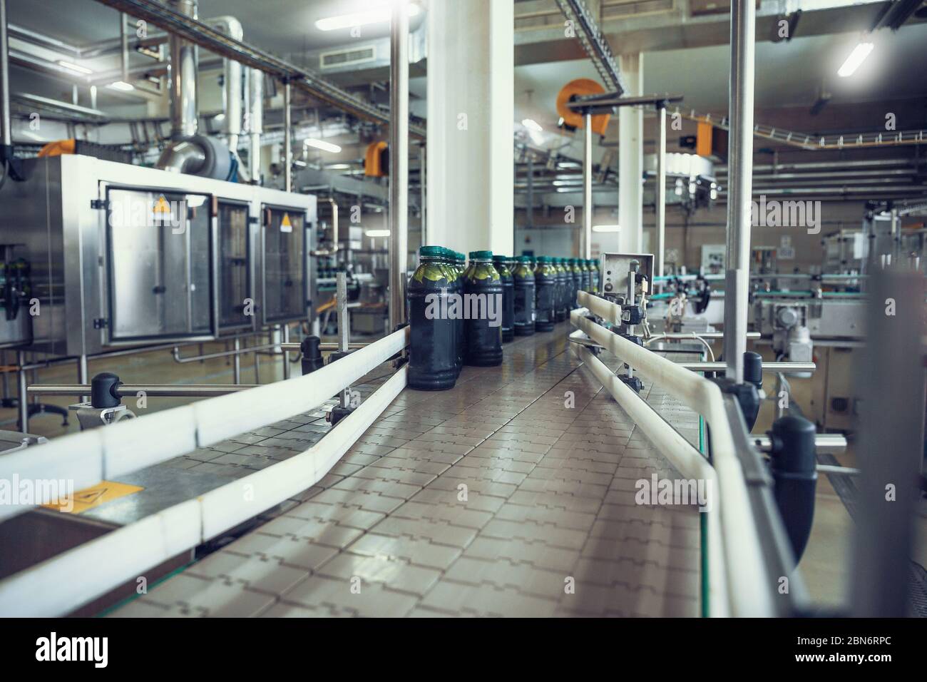 Nastro trasportatore o linea con bottiglie di succo su macchine per attrezzature di fabbrica di bevande. Foto Stock