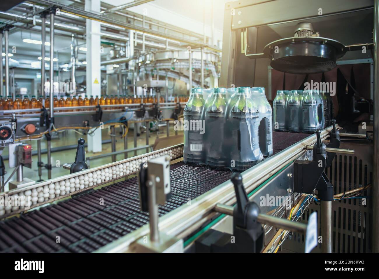 Nastro trasportatore o linea con bottiglie di succo confezionate e pronto per la consegna o la spedizione su macchinari per attrezzature di fabbrica di bevande. Foto Stock