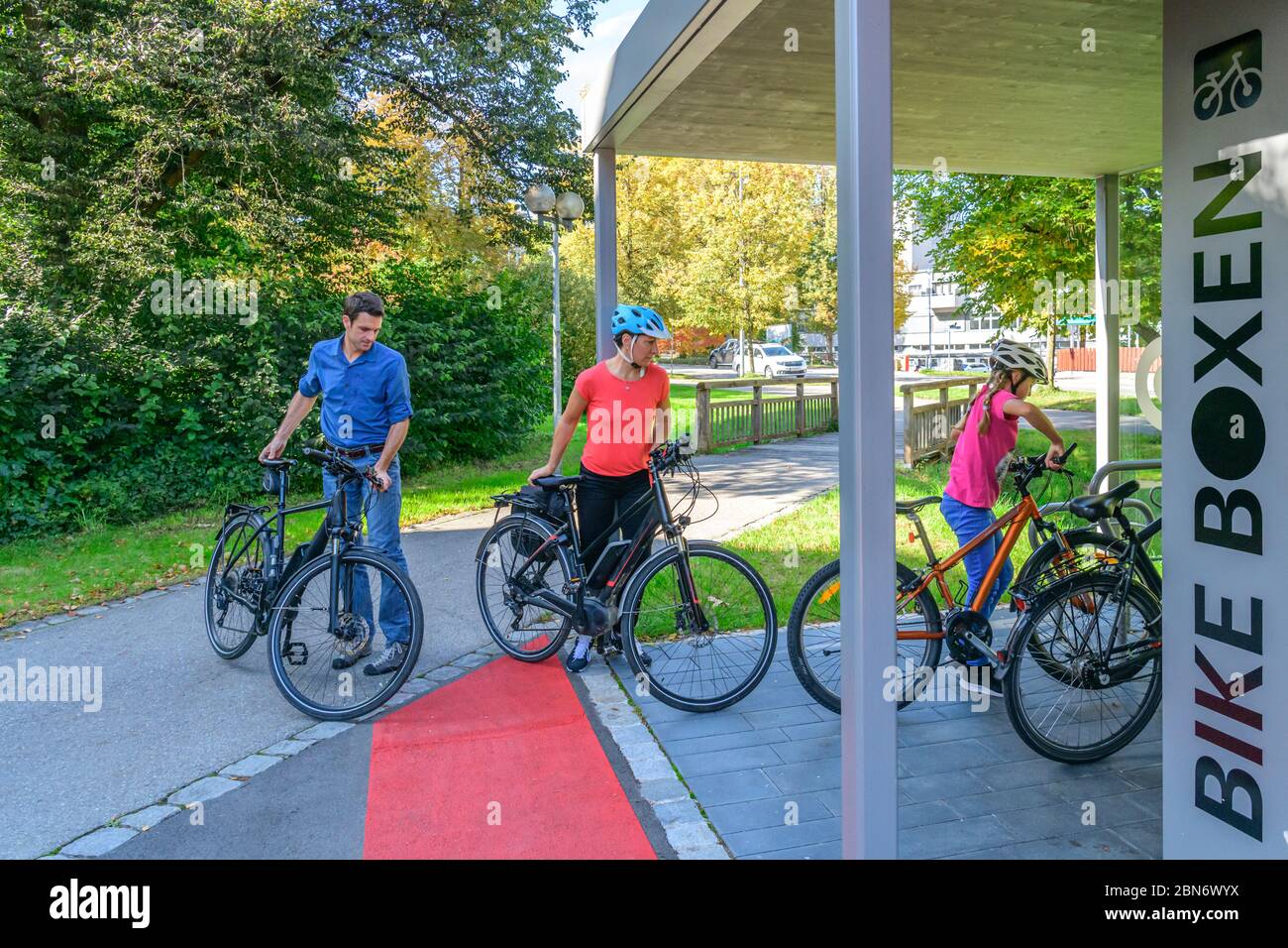 La famiglia, molto umorata, utilizza un concetto esemplare di parcheggio per biciclette per una passeggiata a piedi Foto Stock