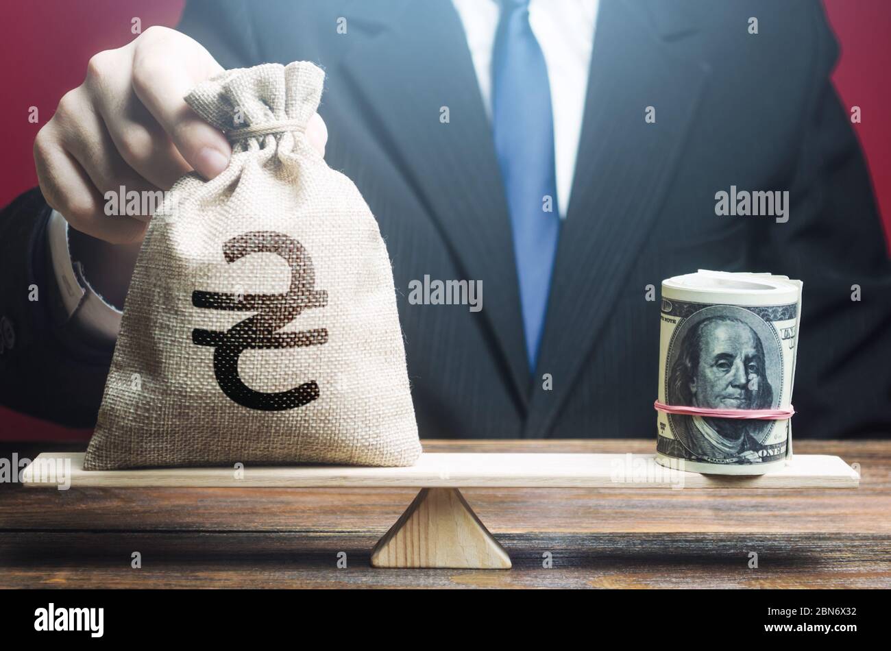 L'uomo mette un sacchetto di soldi ucraino di hryvnia su scale opposte al pacchetto del dollaro. Politica monetaria. Tasso di cambio, indicatori economici di confronto. Centro di Ba Foto Stock