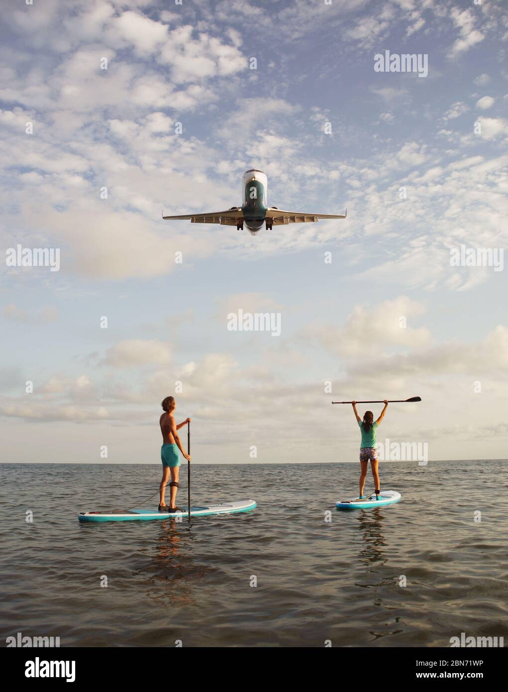 Giovane coppia che si accoppia a bordo del SUP con atterraggio aereo su sfondo Foto Stock