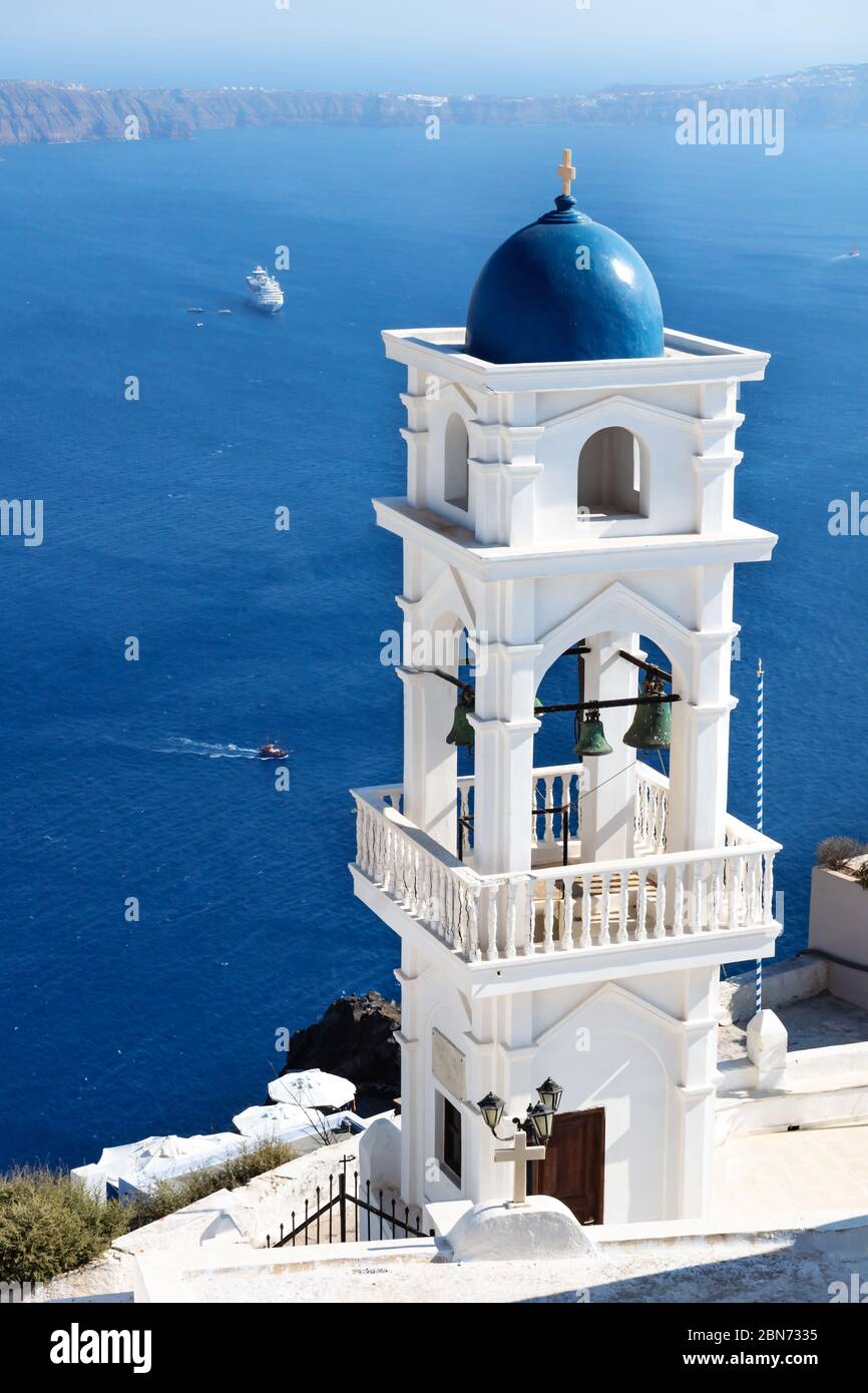 La torre della chiesa di Anastasi con l'oceano con nave da crociera sullo sfondo in una giornata nuvolata di sole, Imerovigli, Santorini, Grecia Foto Stock