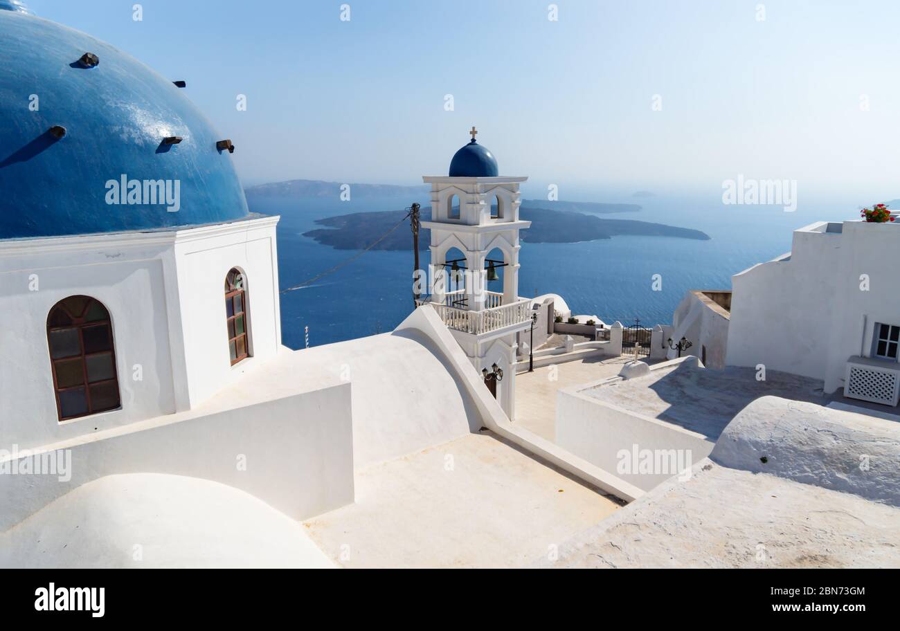 La cupola e la torre della chiesa di Anastasi con l'oceano e le isole sullo sfondo in una giornata nuvolata di sole, Imerovigli, Santorini, Grecia Foto Stock